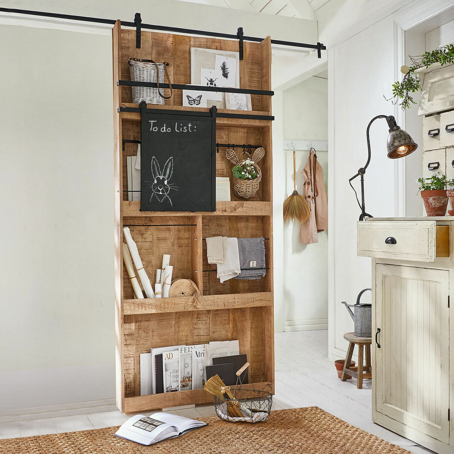 Porte coulissante Vulmont Étagère en bois avec tableau noir et décorations dans un intérieur clair avec tapis en jute