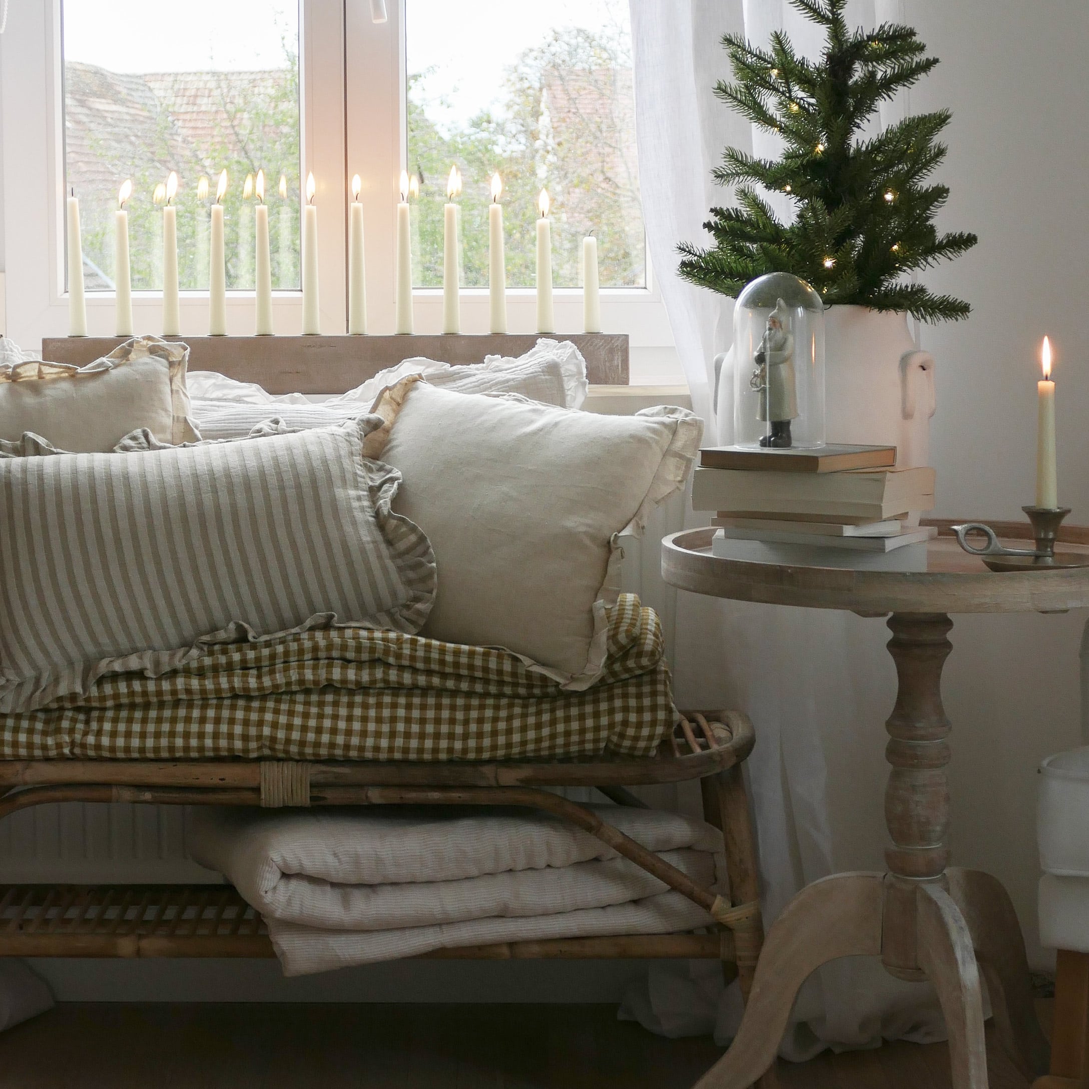 Coin cosy avec coussins beiges, table en bois avec décorations et bougies allumées