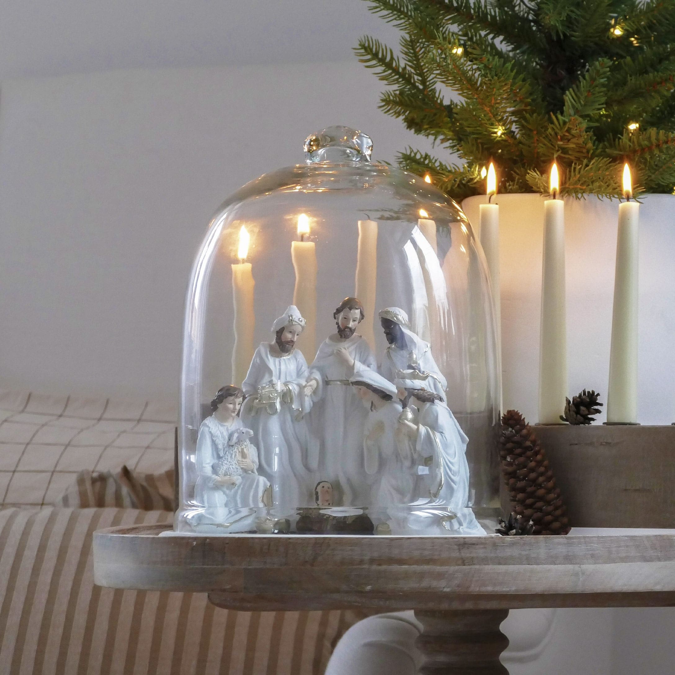 Crèche de Noël en céramique blanche sous cloche en verre avec bougies allumées et décoration festive