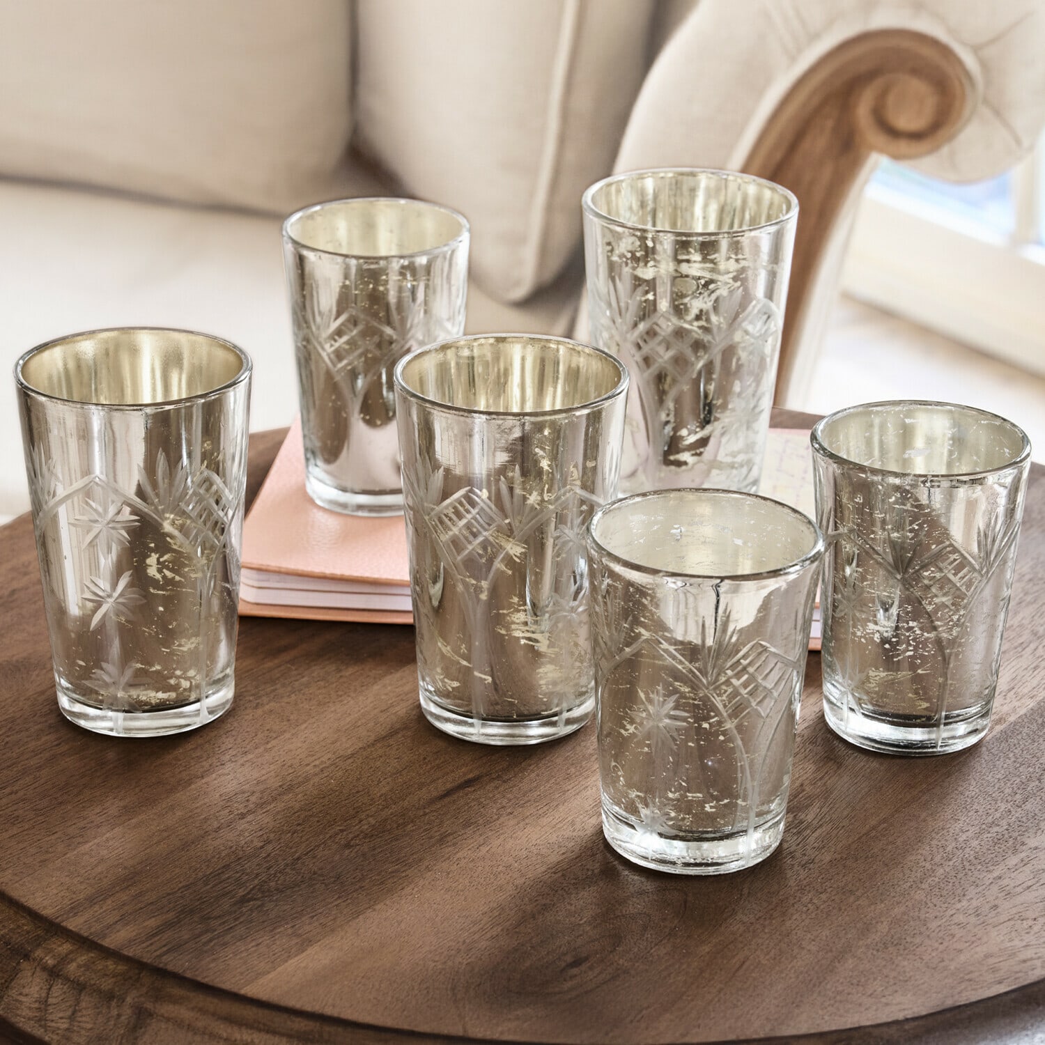 Ensemble de six photophores en verre gravé avec finition argentée posés sur une table en bois