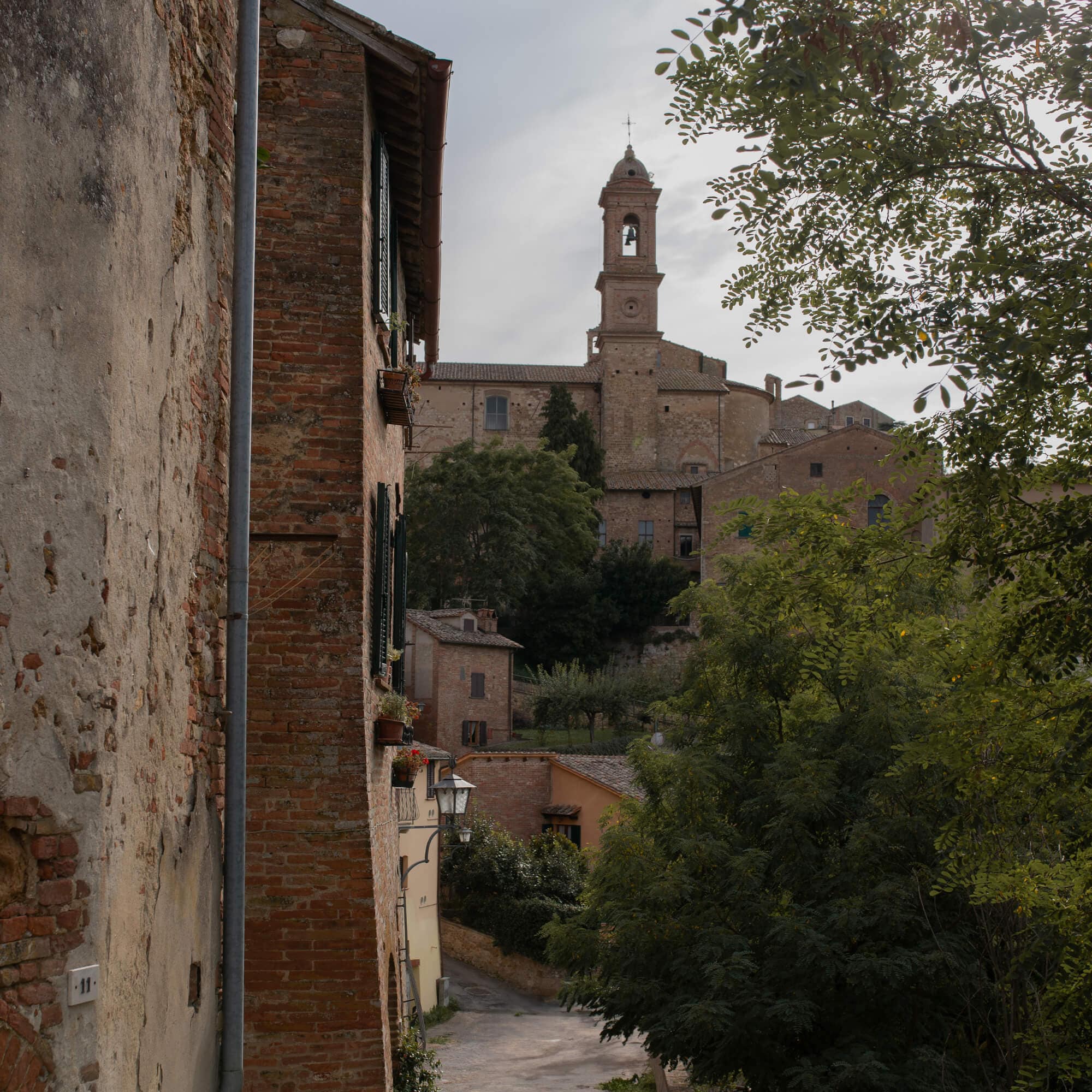 Vue d'une rue ancienne en pierre avec bâtiments en briques et clocher d'église en arrière-plan
