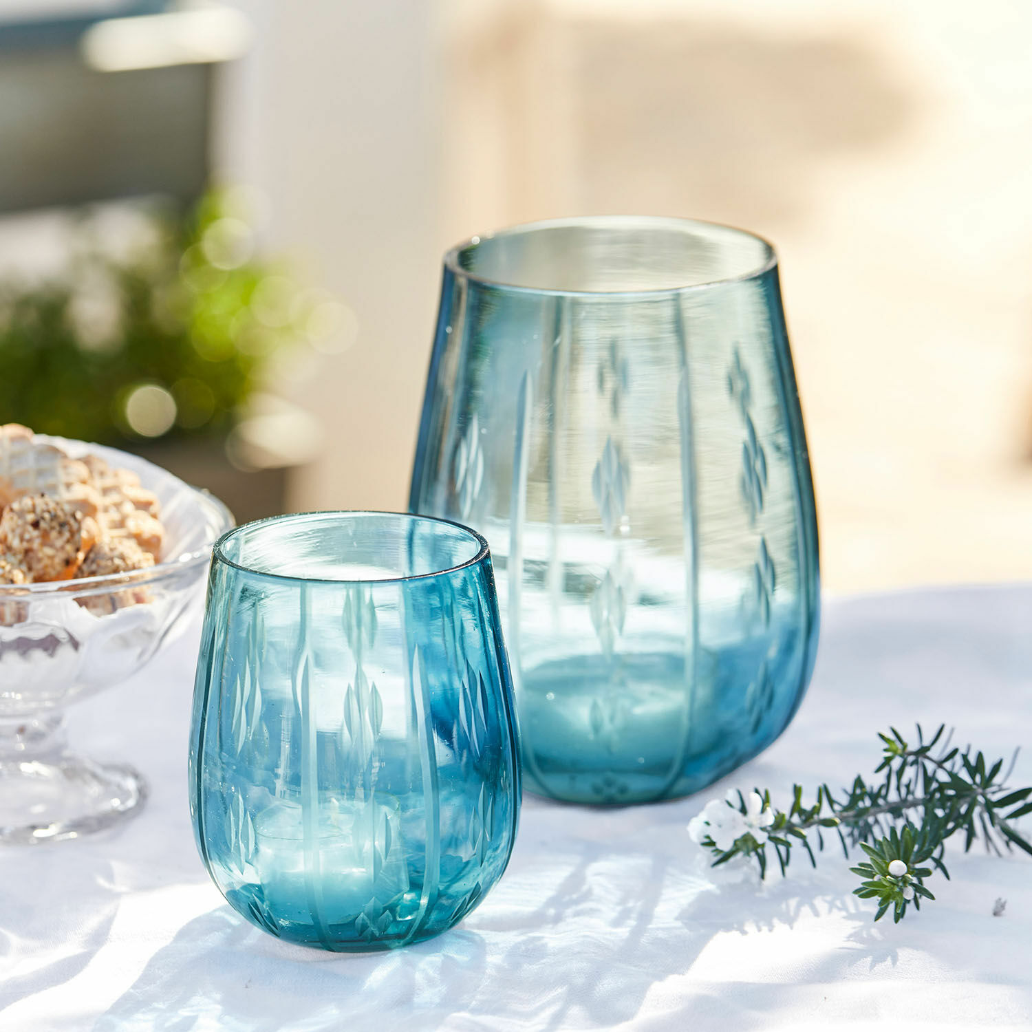 Lot de 2 photophores Danisar Deux photophores en verre bleu avec motif gravé sur fond blanc, décoration de table élégante