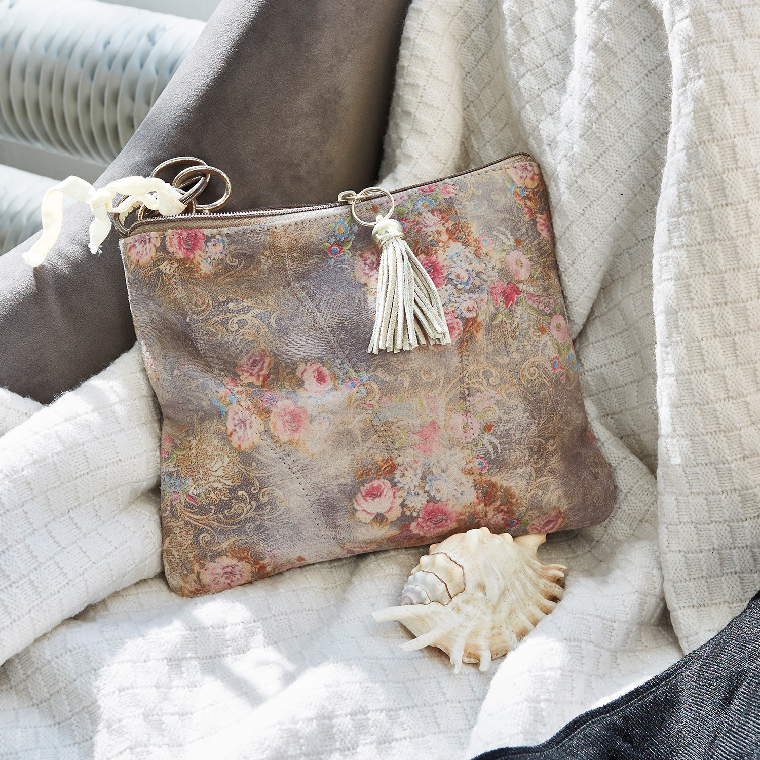 Pochette Ottilie Pochette en daim à motif floral avec pompon dans des tons beige et rose sur fond clair