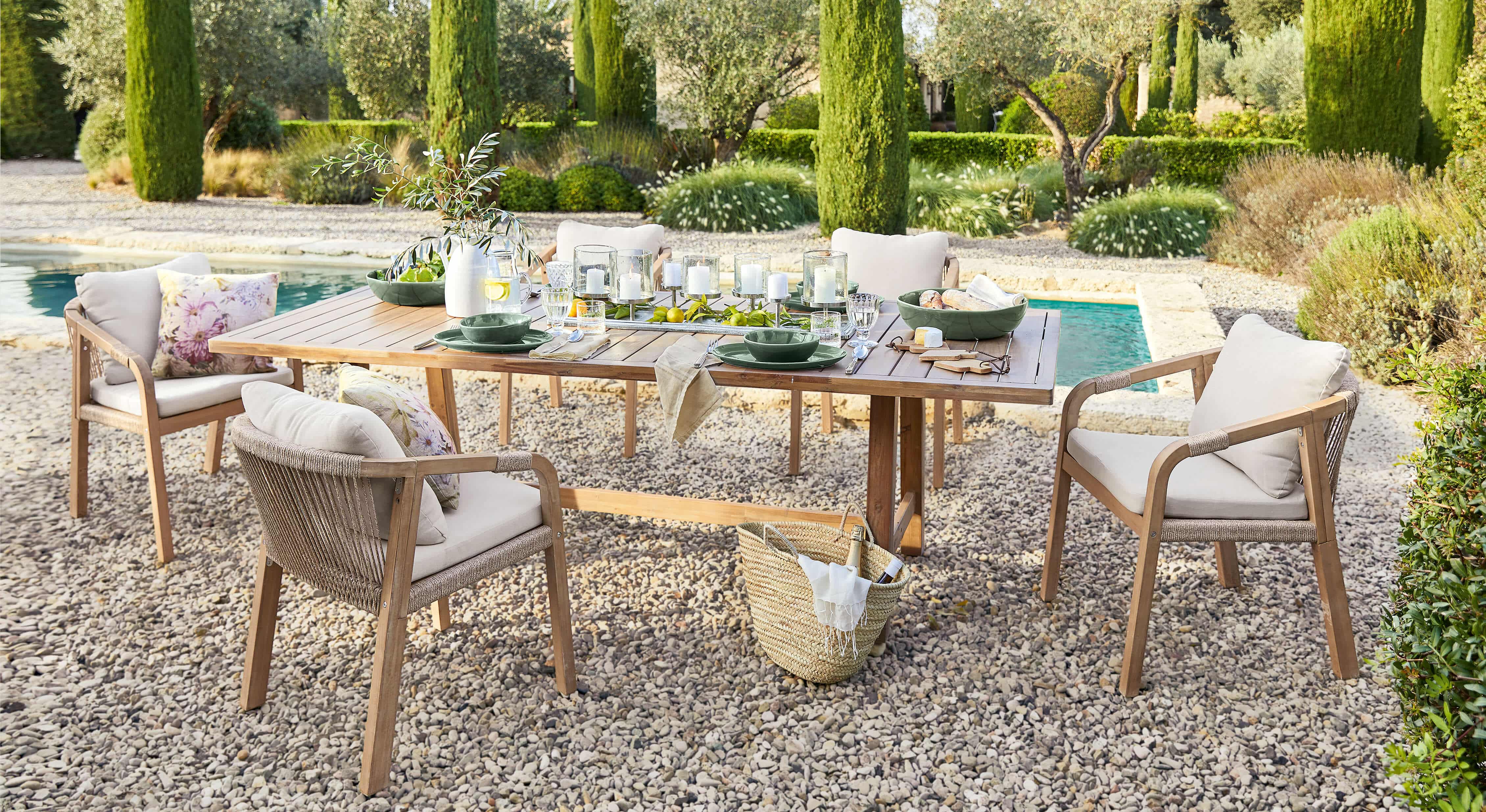 Ensemble de mobilier de jardin avec table en bois et chaises beige sur patio en gravier près de la piscine
