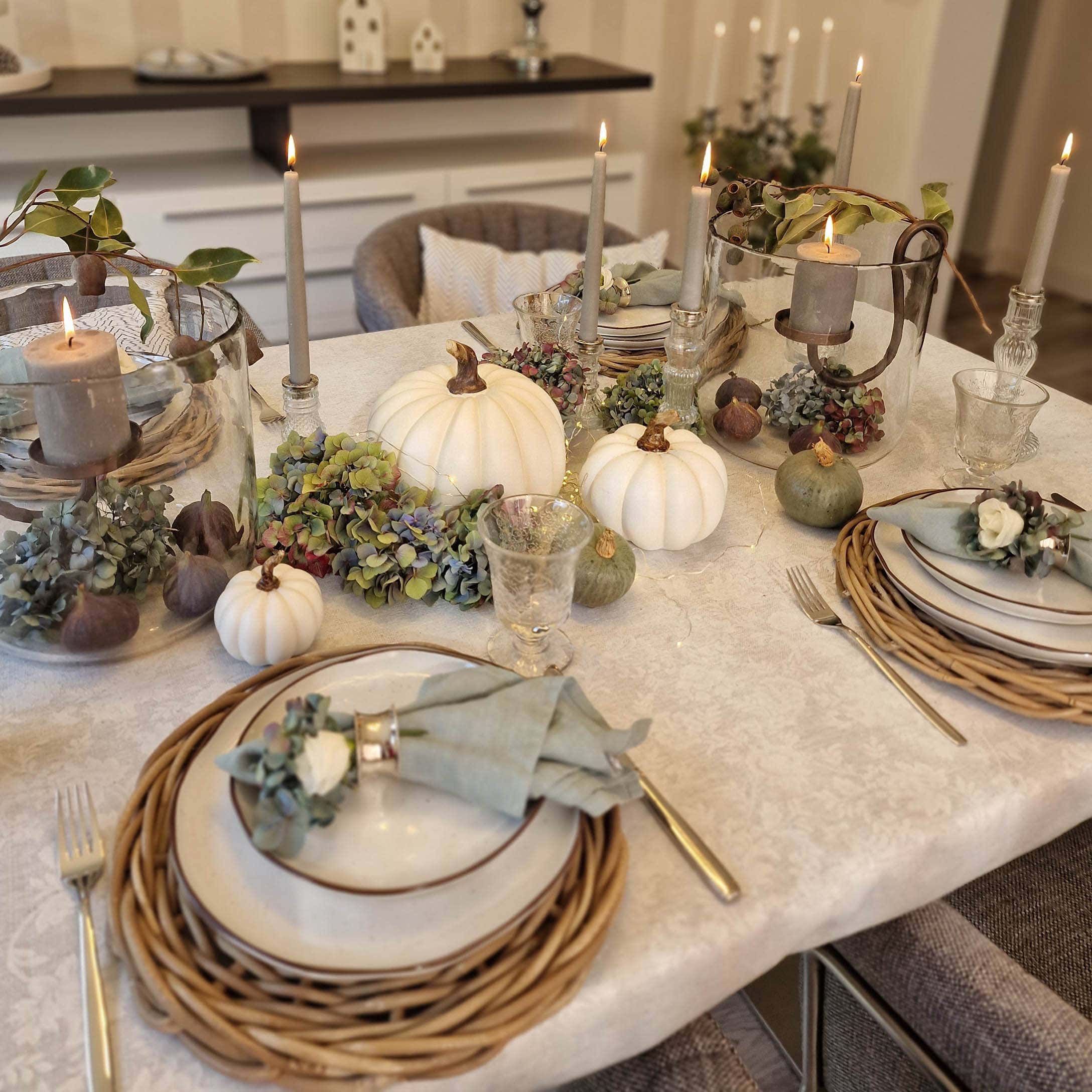 Décoration de table automnale élégante avec citrouilles blanches, bougies et éléments naturels sur nappe