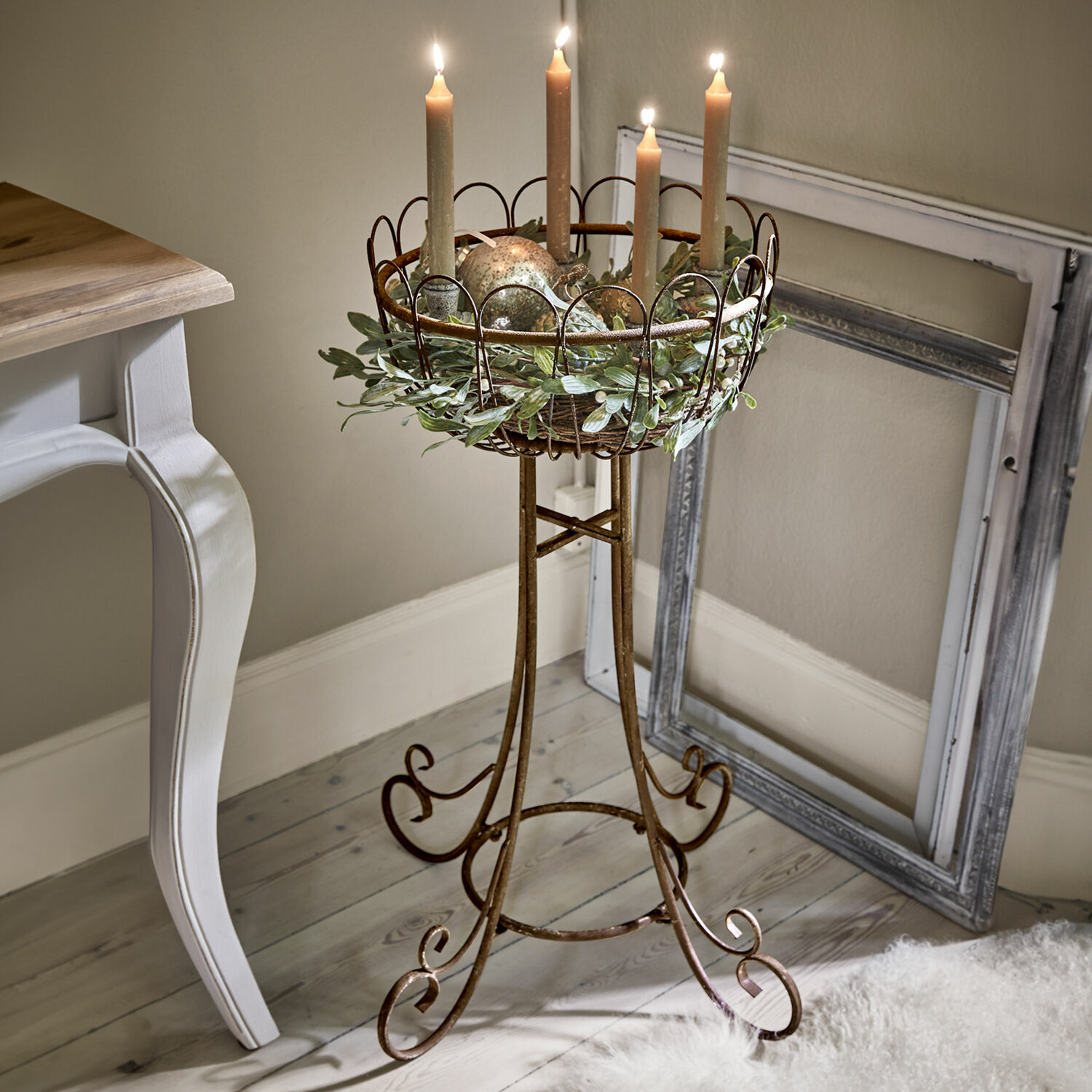 Support de décoration Évariste Support à bougies en métal brun avec couronne décorative et quatre bougies allumées dans un intérieur cosy
