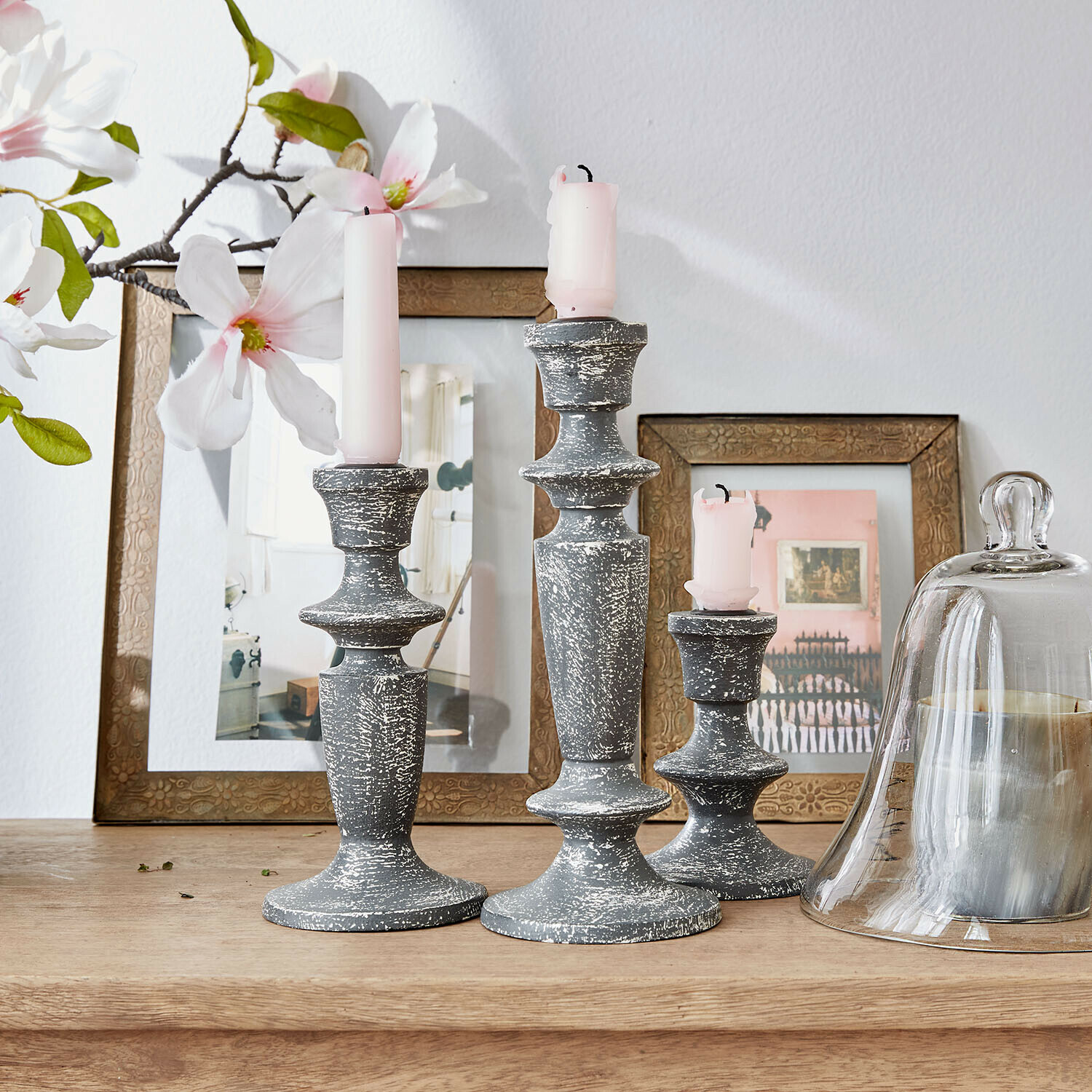 Lot de 3 bougeoirs Ténébrelle Ensemble de trois bougeoirs en bois gris vieilli avec bougies roses sur une table en bois