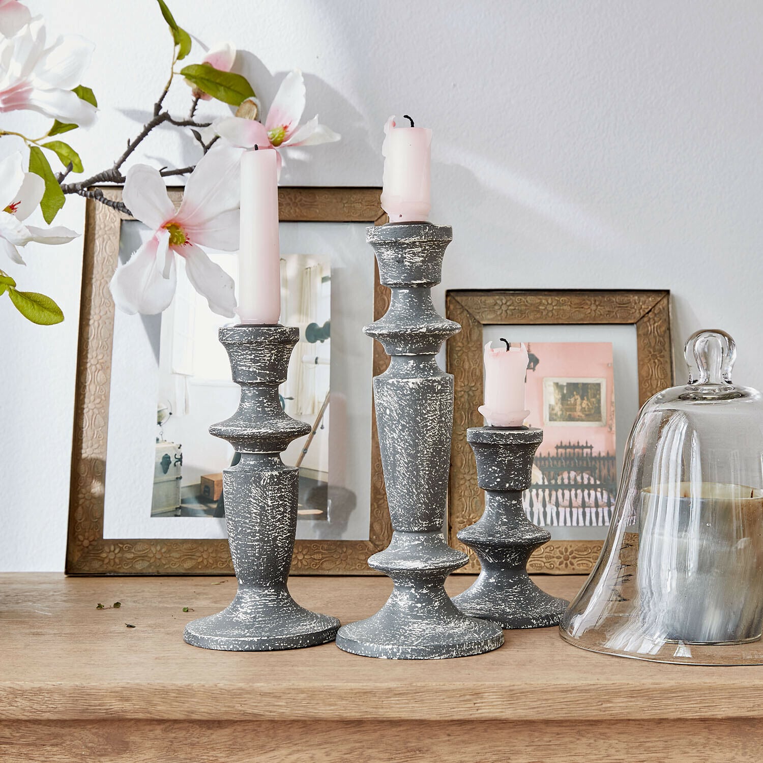 Lot de 3 bougeoirs Ténébrelle Ensemble de trois bougeoirs en bois gris vieilli avec bougies roses sur une table en bois