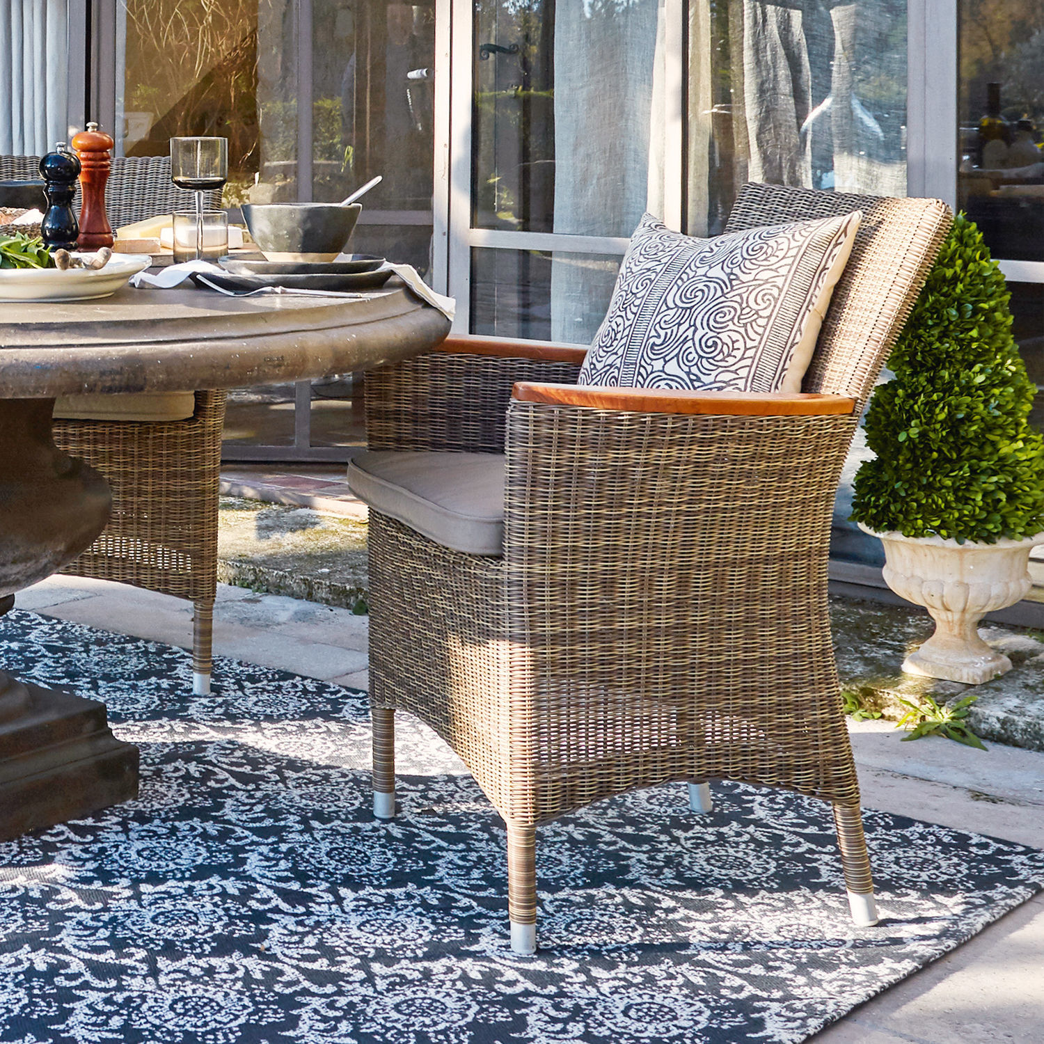 Fauteuil Casper Chaise en rotin naturel avec coussin et accoudoirs en bois sur terrasse extérieure