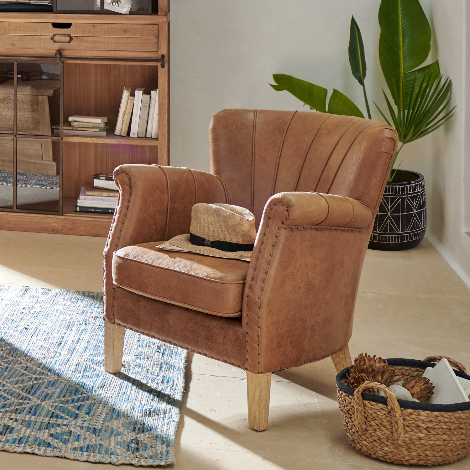 Fauteuil Bartley Fauteuil marron en similicuir avec pieds en bois dans un intérieur clair avec un chapeau posé dessus