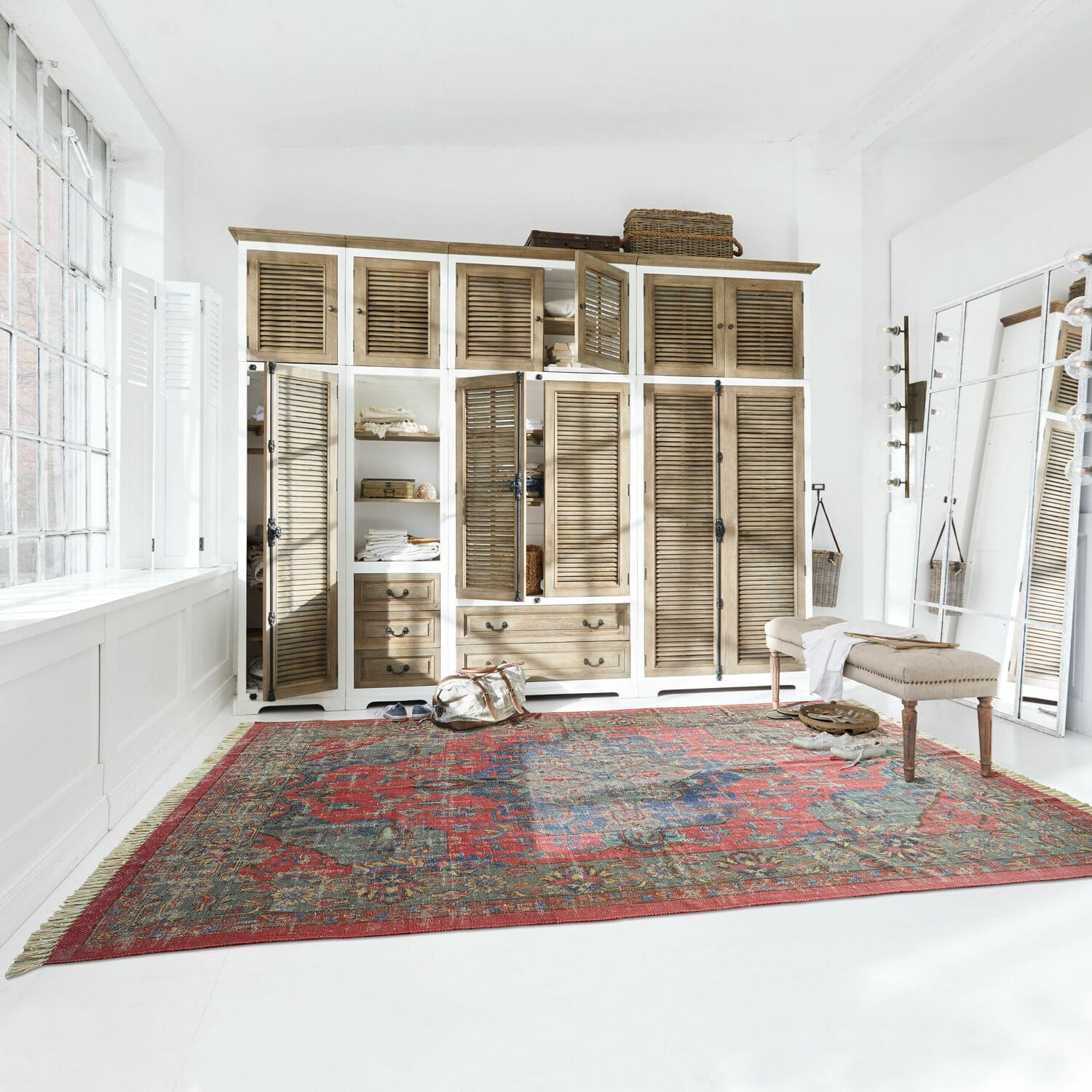 Tapis Southampton Grand tapis rouge à motif oriental dans une pièce claire avec armoire en bois et banc