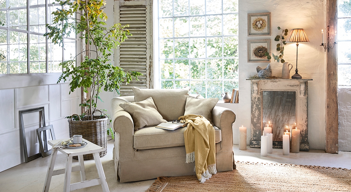 Fauteuil beige confortable avec coussins et plaid jaune dans un salon lumineux au style naturel