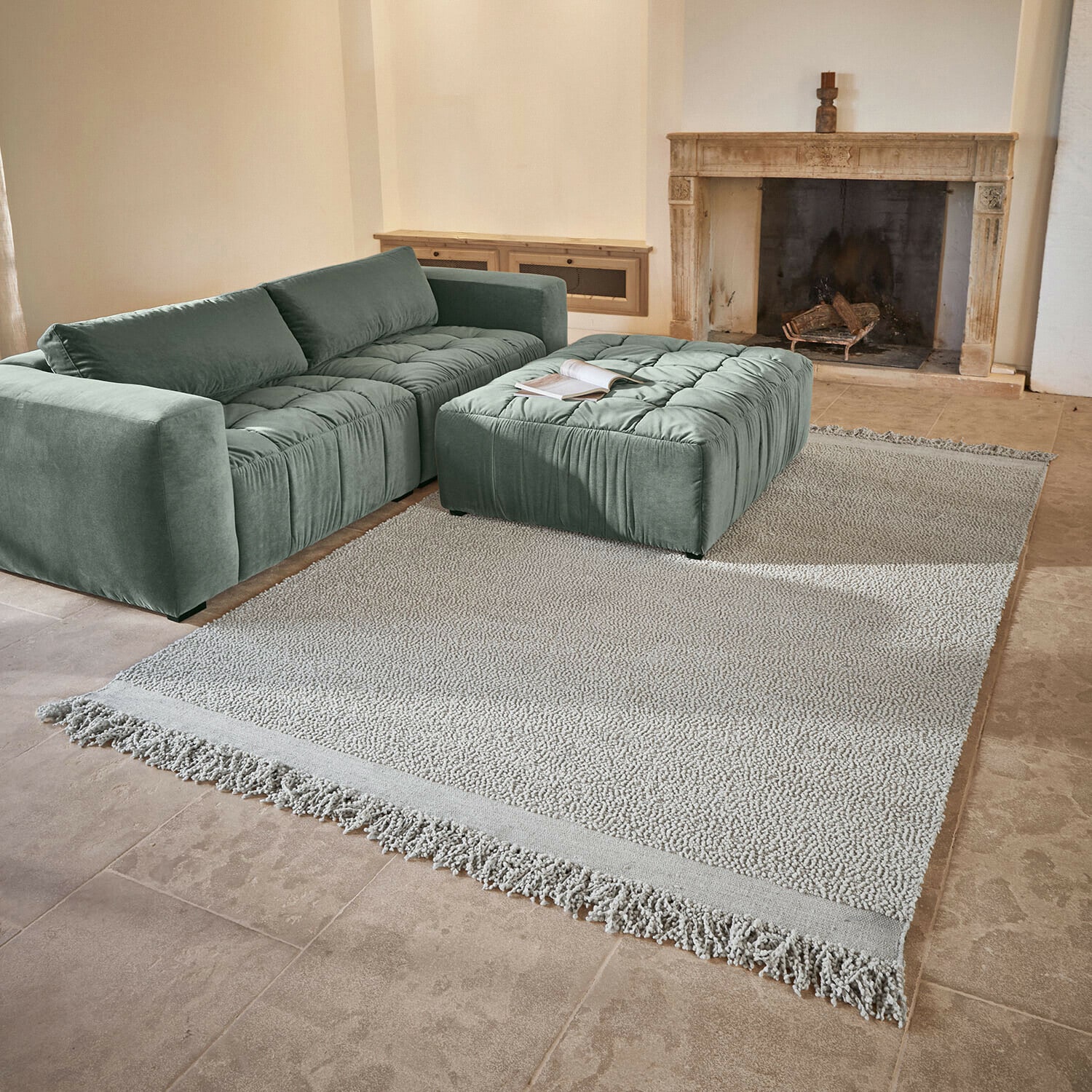 Tapis Linnet Canapé vert en velours avec assise capitonnée et pouf assorti sur tapis clair près d'une cheminée