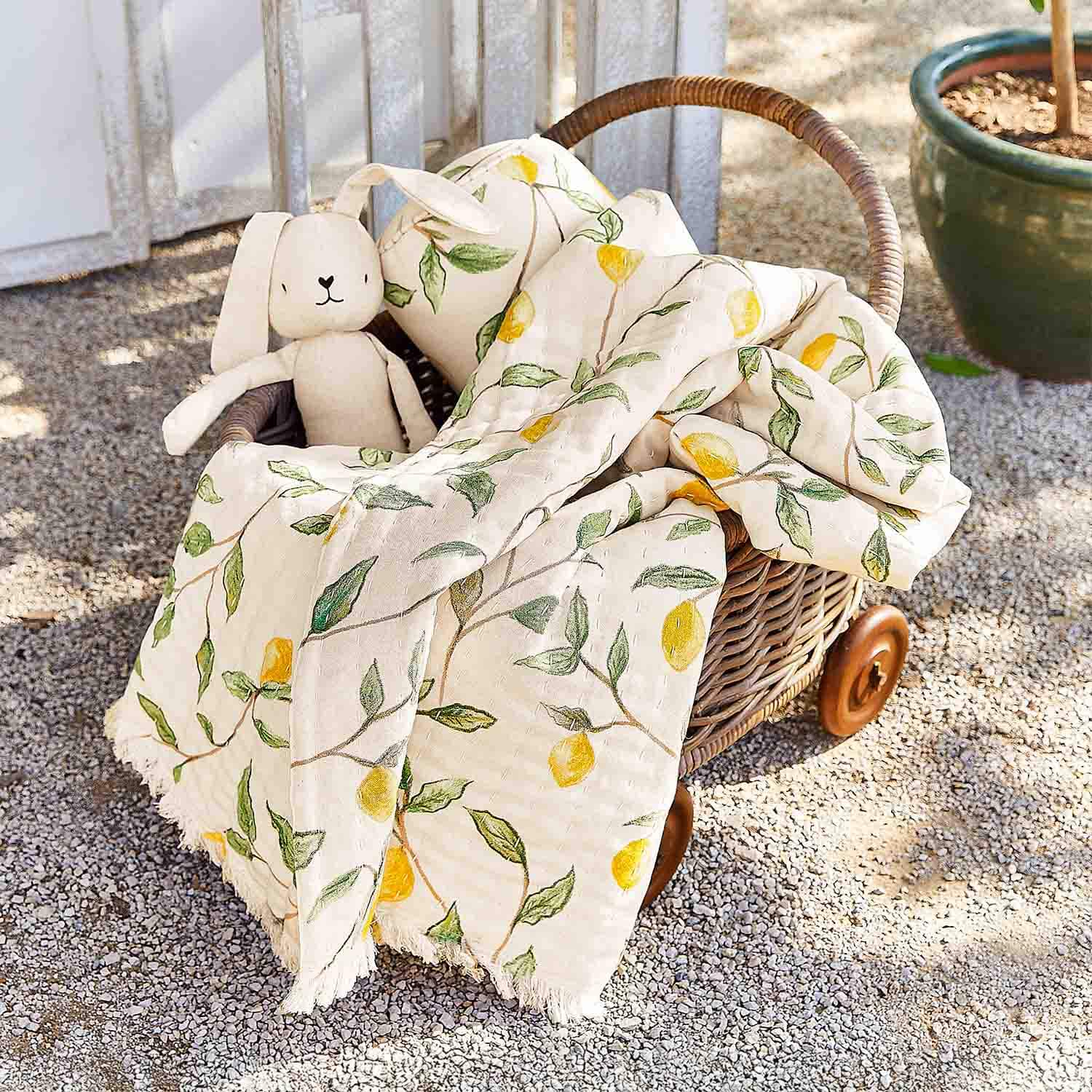 Panier en osier sur roulettes avec couverture en coton crème à motif citron et peluche lapin