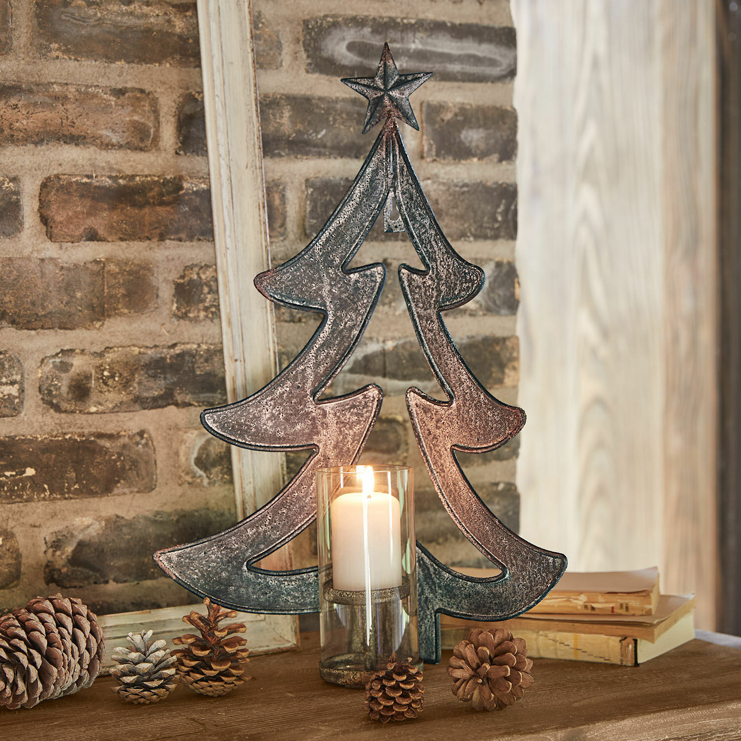 Bougeoir mural Jolise Décoration de sapin en métal avec étoile et bougie dans un photophore en verre sur table en bois avec pommes de pin