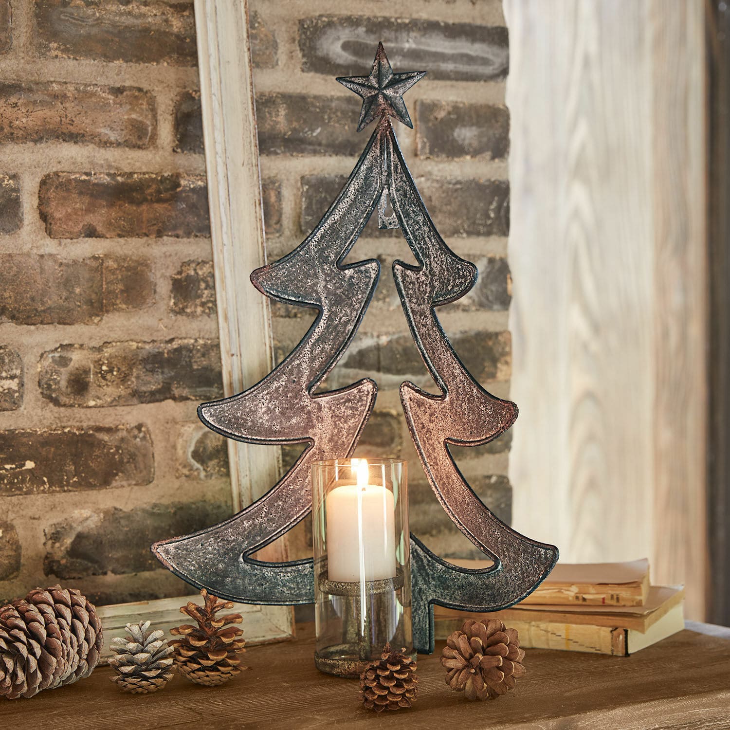 Bougeoir mural Jolise Décoration de sapin en métal avec étoile et bougie dans un photophore en verre sur table en bois avec pommes de pin