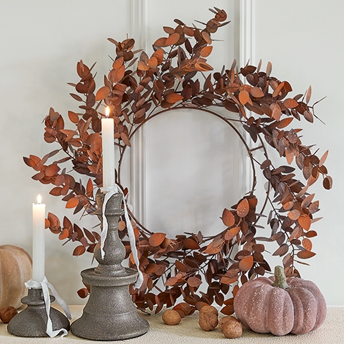 Couronne décorative en métal rouillé avec deux bougies et une citrouille décorative sur une table
