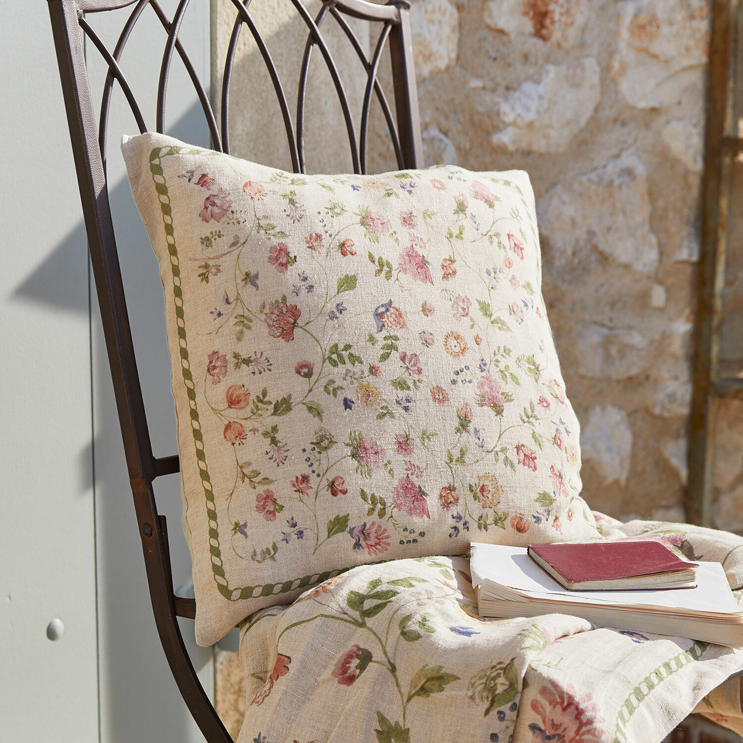 Housse de coussin Karratha Coussin et plaid en lin à motif floral pastel posés sur une chaise en métal pour décoration intérieure