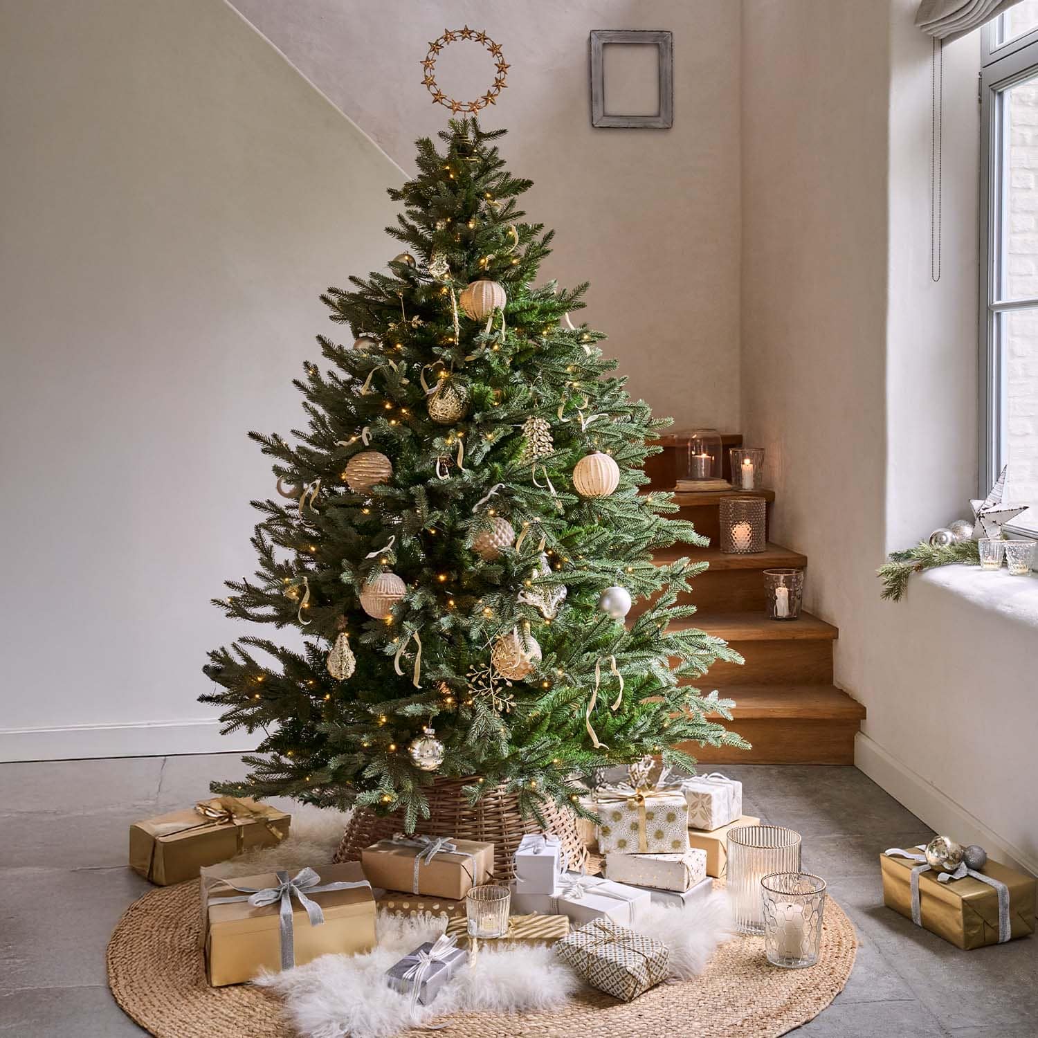 Sapin vert décoré d'ornements naturels et cadeaux dorés sur un tapis rond dans une pièce lumineuse