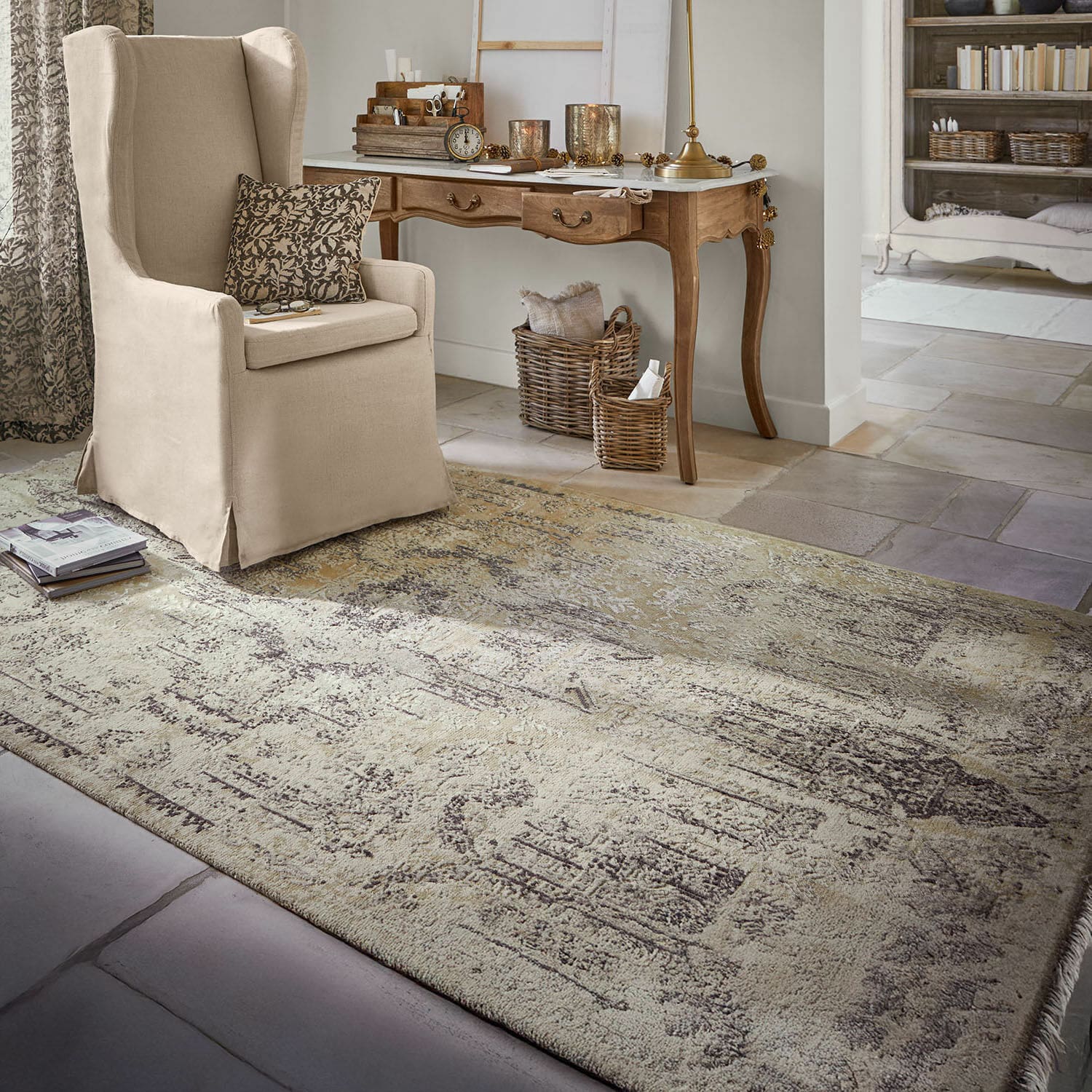 Tapis Marzahan Tapis beige à motif vintage dans un salon avec fauteuil beige et bureau en bois, décorations et livres