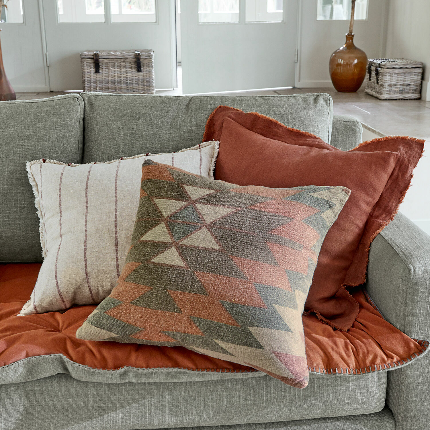 Lot de 3 housses de coussins Florentin Ensemble de trois coussins décoratifs en tissu aux tons chauds sur un canapé gris