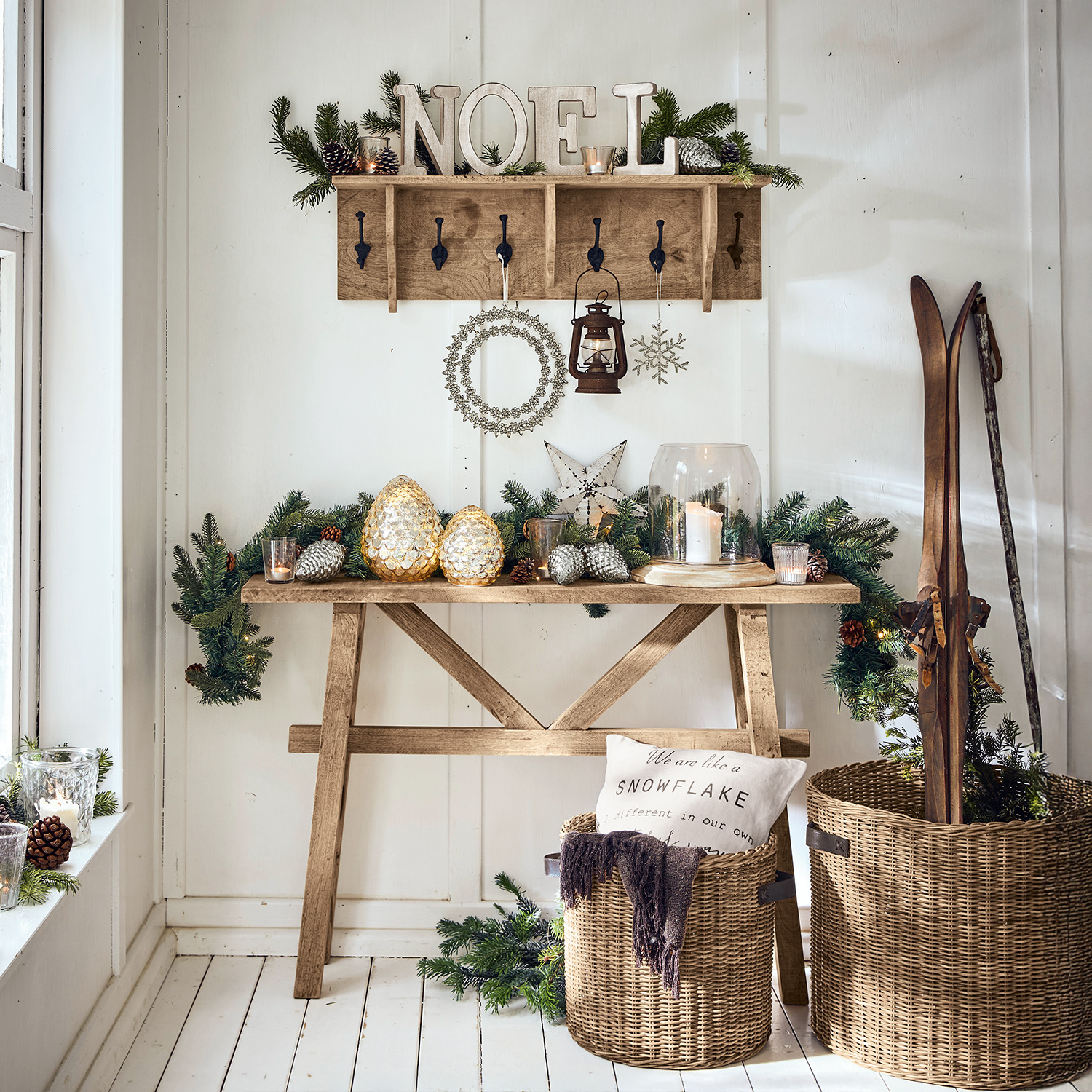 Table en bois et porte-manteau avec décorations de Noël, lanterne et paniers en osier avec skis