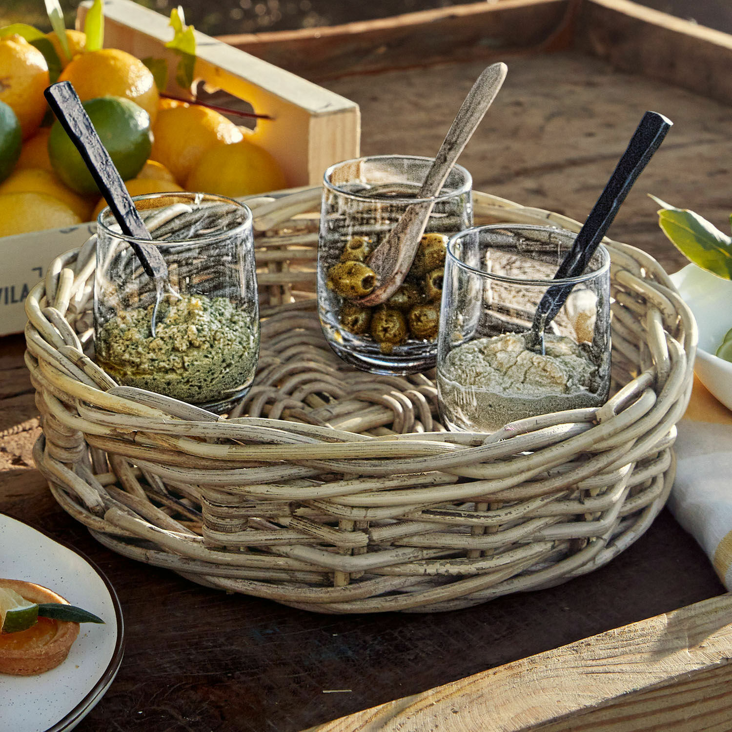 Plateau Duras Panier rond en osier avec trois verres contenant des épices et des olives sur une table en bois