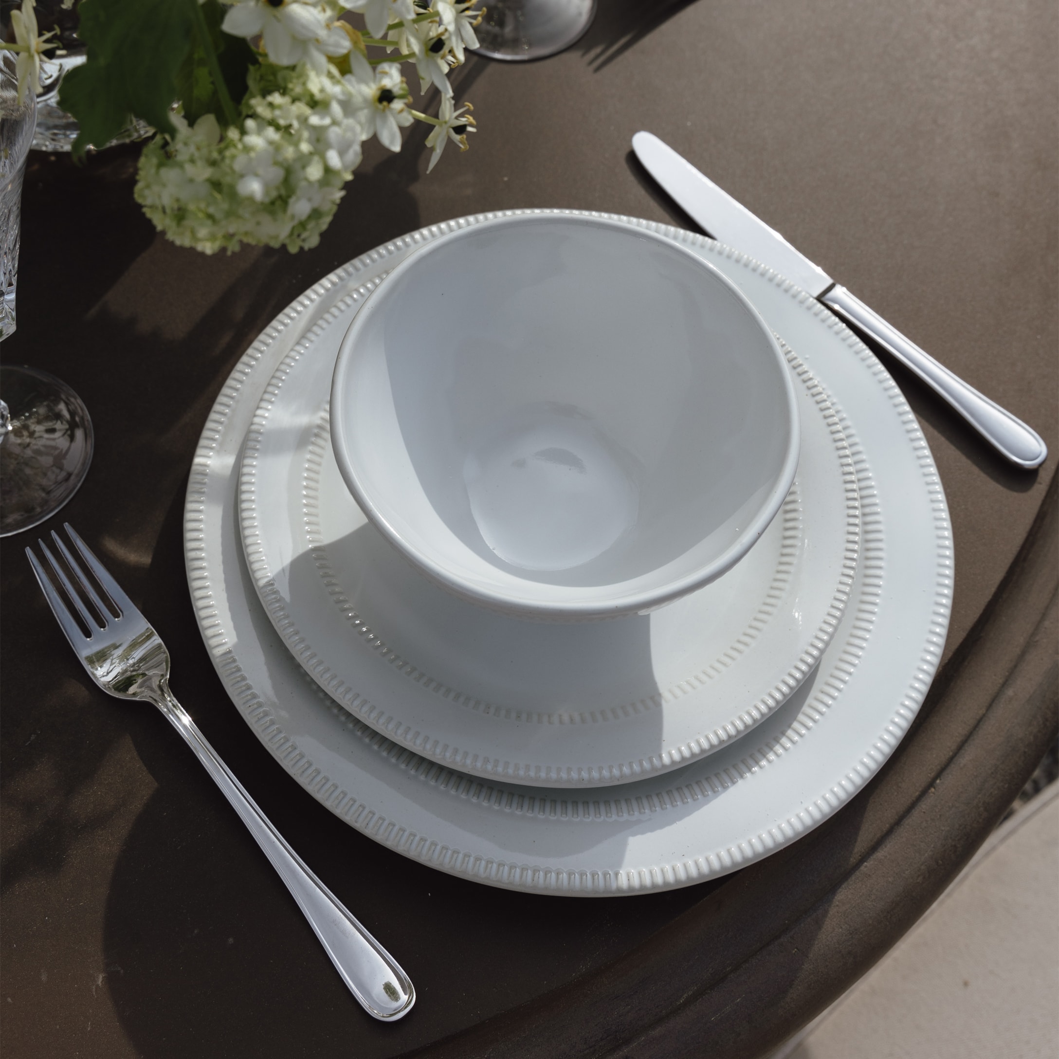 Service de vaisselle en porcelaine blanche avec bol et assiettes sur table marron avec couverts