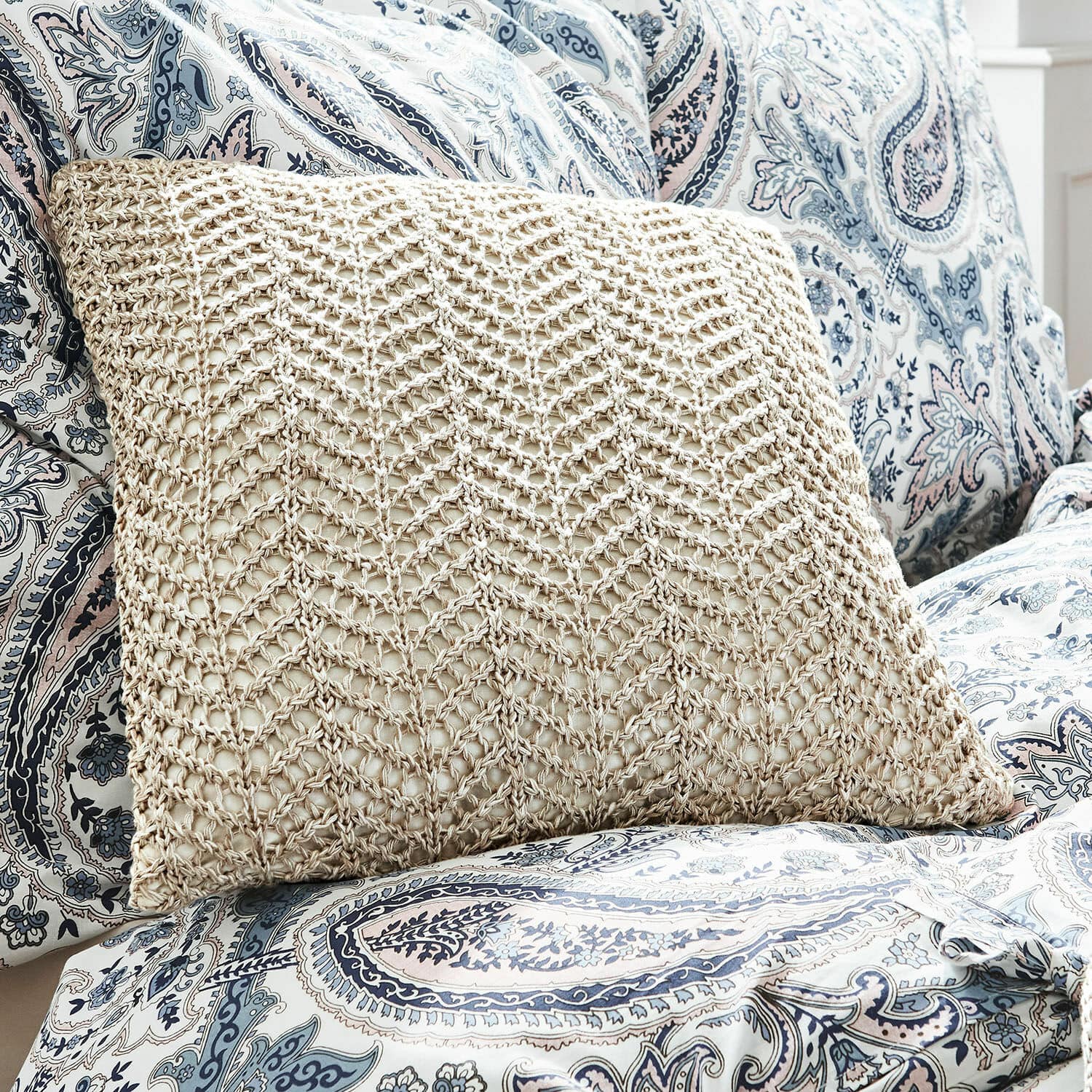 Coussin beige à motif tressé sur housse bleue et blanche avec motif paisley