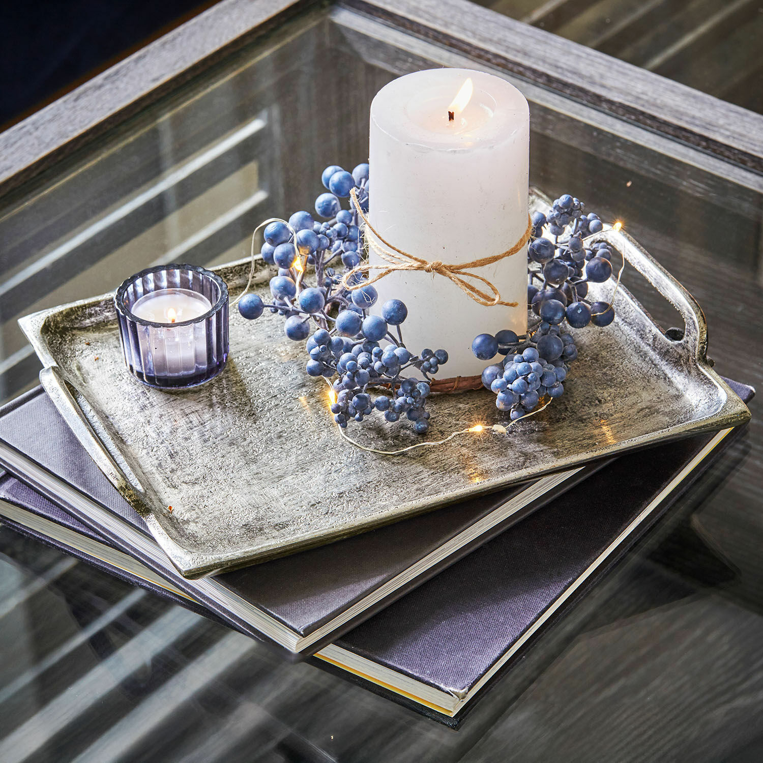 Lot de 2 plateaux Branora Bougie blanche avec corde naturelle et décor de baies bleues sur plateau en métal posé sur table en verre