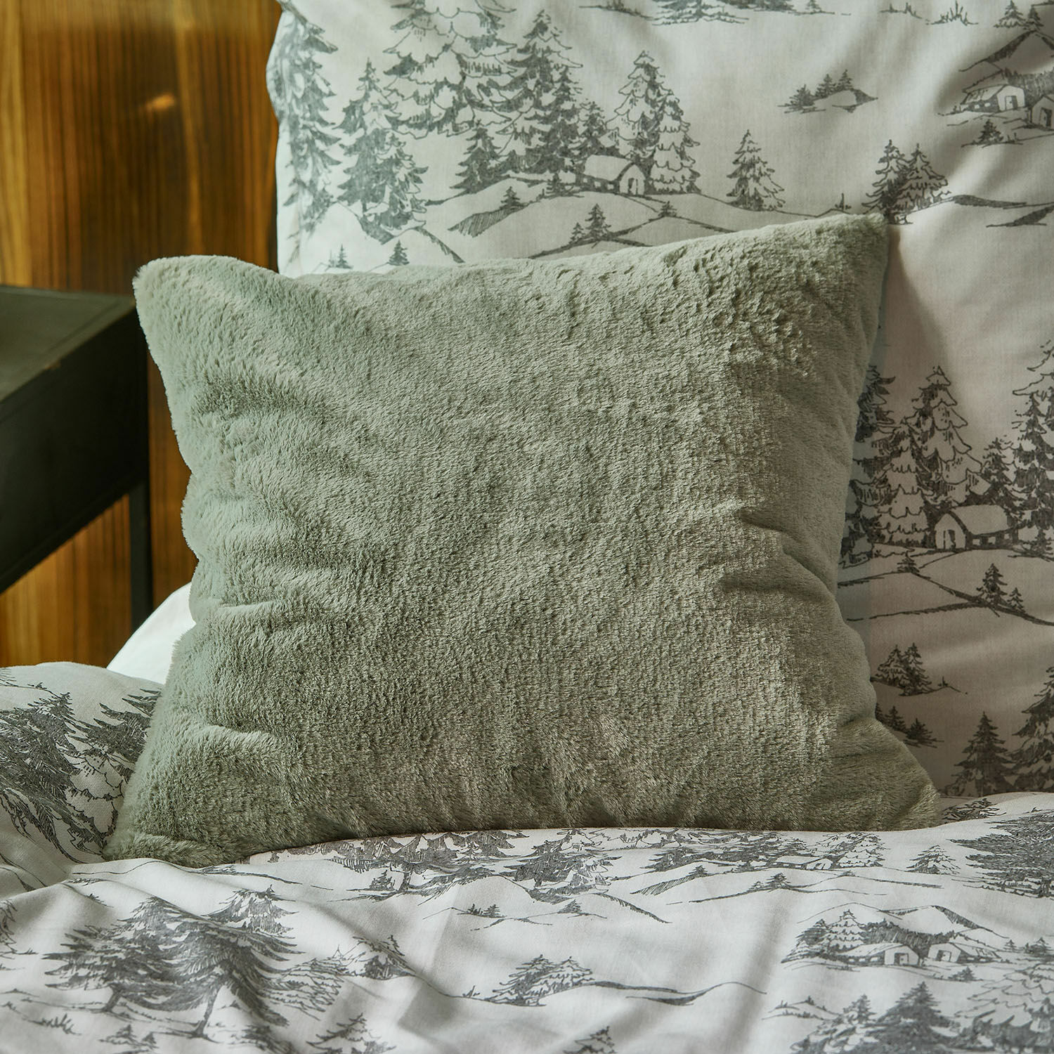 Housse de coussin Léorienne Coussin vert en peluche douce sur un lit avec une housse de couette à motifs d'arbres et maisons gris