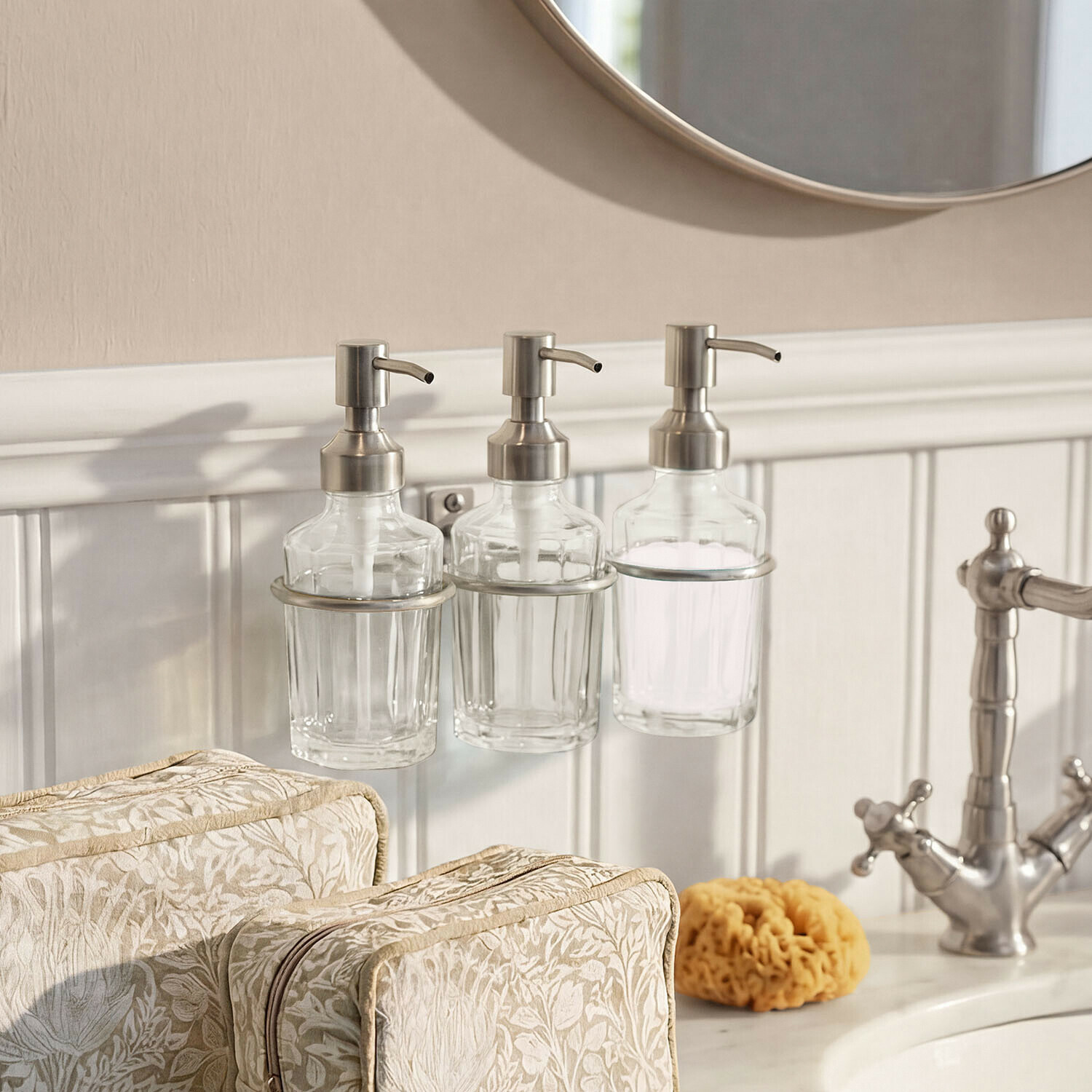 Distributeur de savon Virellane Trois distributeurs de savon en verre avec pompes métalliques fixés près du lavabo et miroir