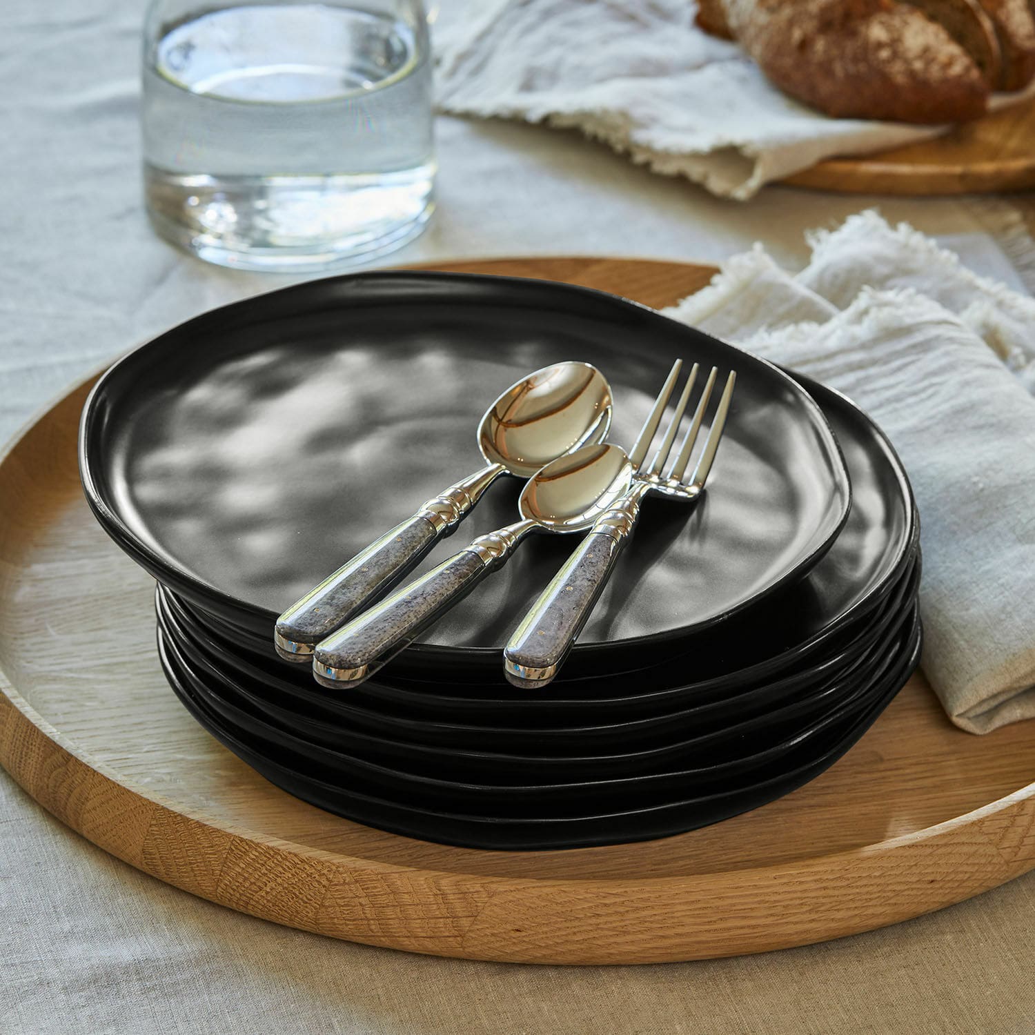 Lot de 6 assiettes Biarré Ensemble d'assiettes en céramique noire empilées sur un plateau en bois avec couverts et fleur décorative