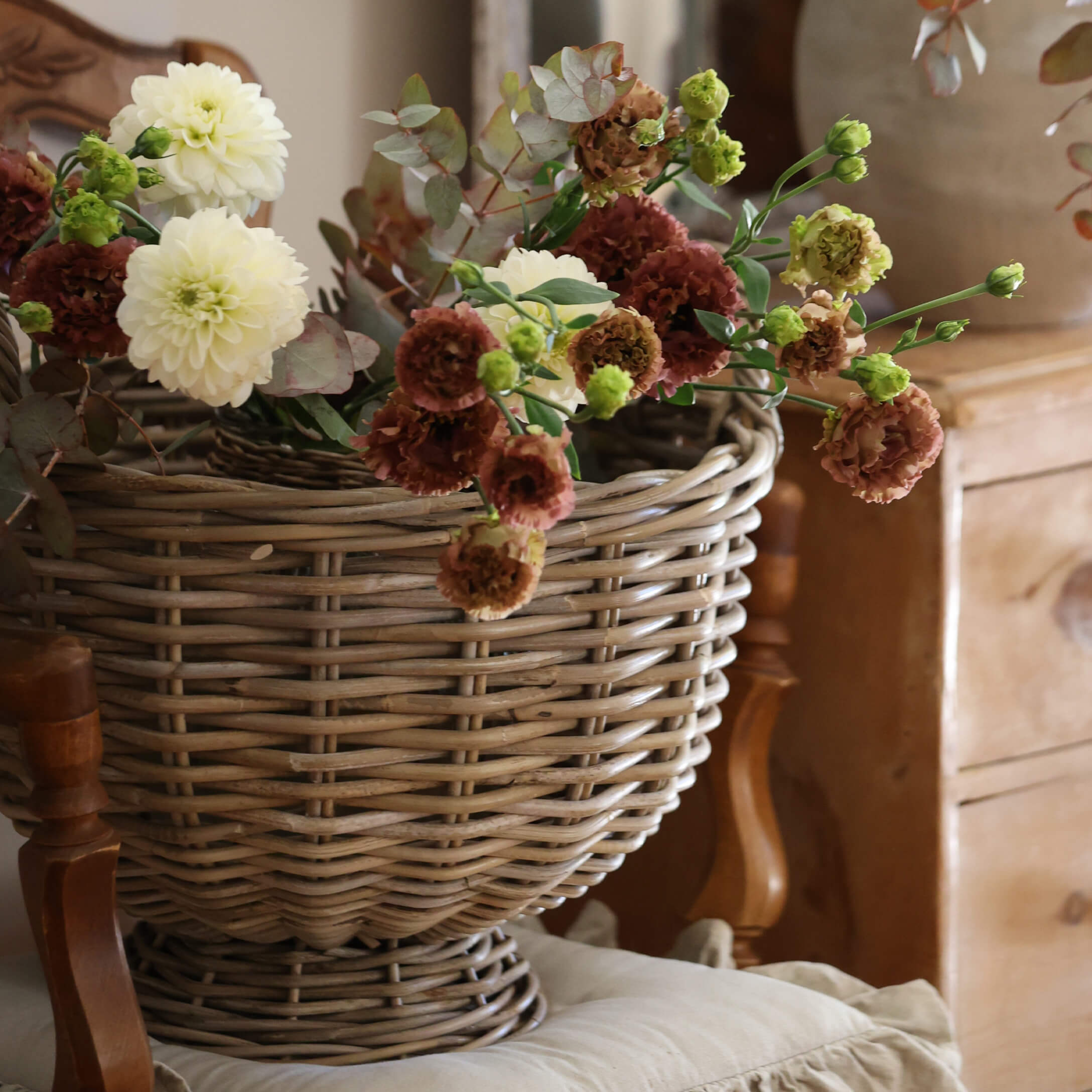 Panier en osier décoratif avec fleurs crème et marron pour une ambiance intérieure vintage