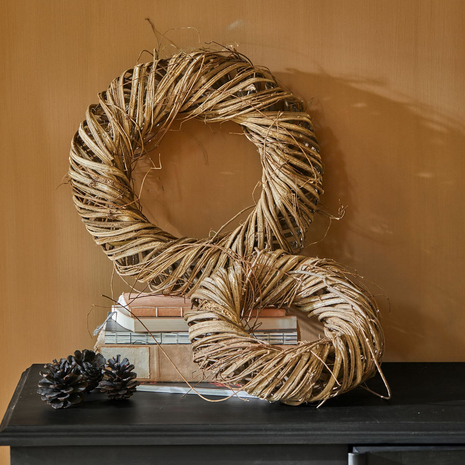 Lot de 2 couronnes Lunéor Couronnes décoratives en osier naturel beige posées sur une table noire avec des livres empilés