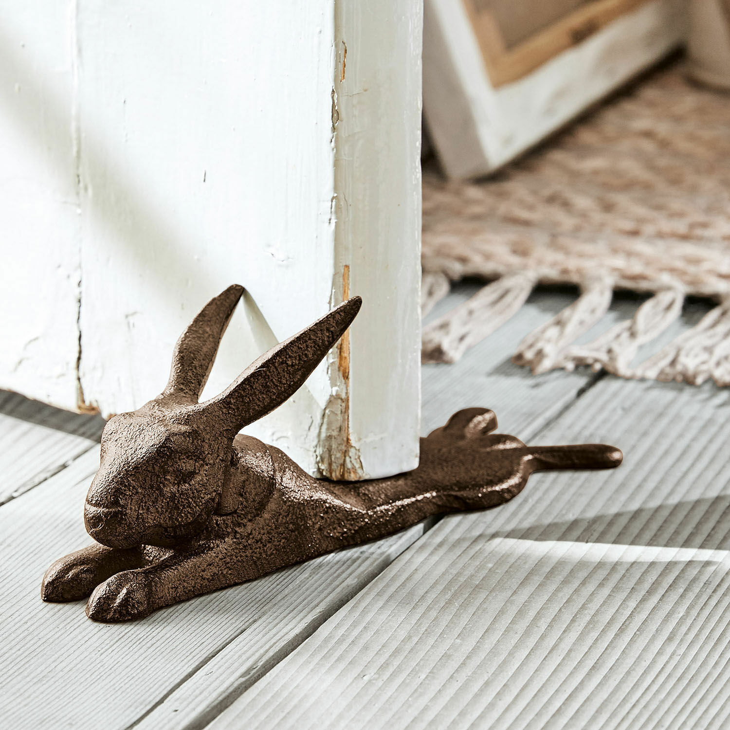 Bloque-porte Hennes Butée de porte en métal brun en forme de lapin posée sur un sol en bois, accessoire décoratif et fonctionnel