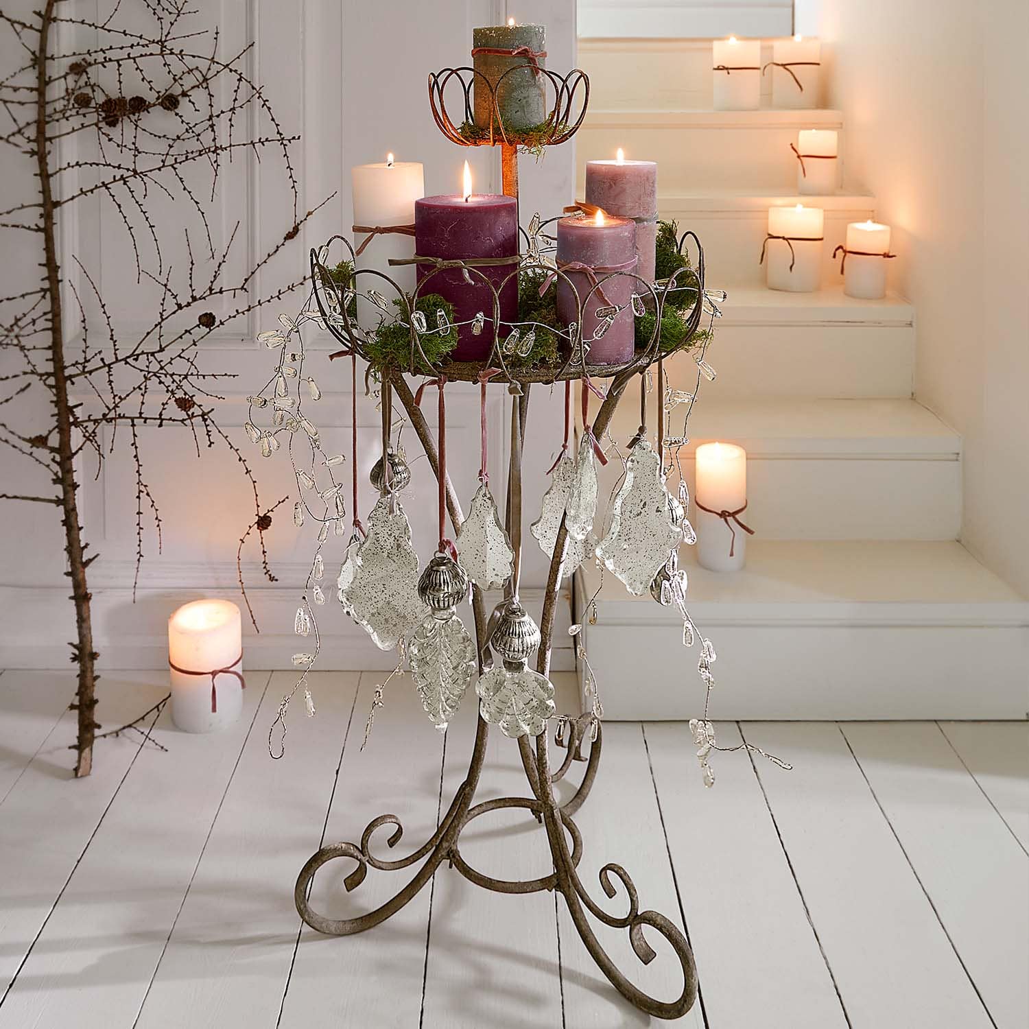 Support en métal pour bougies avec décorations en forme de feuilles et bougies violettes dans un style rustique