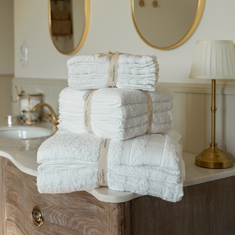 Ensemble de serviettes blanches en coton empilées sur une commode en bois dans une salle de bain élégante