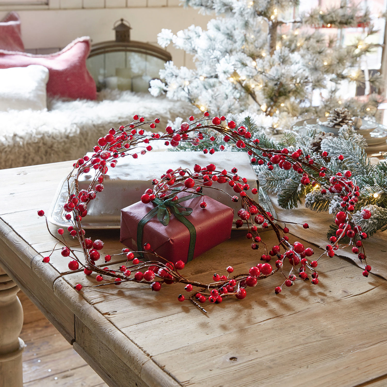 Guirlande Rimont Couronne décorative de baies rouges sur table en bois avec cadeau et décorations de Noël