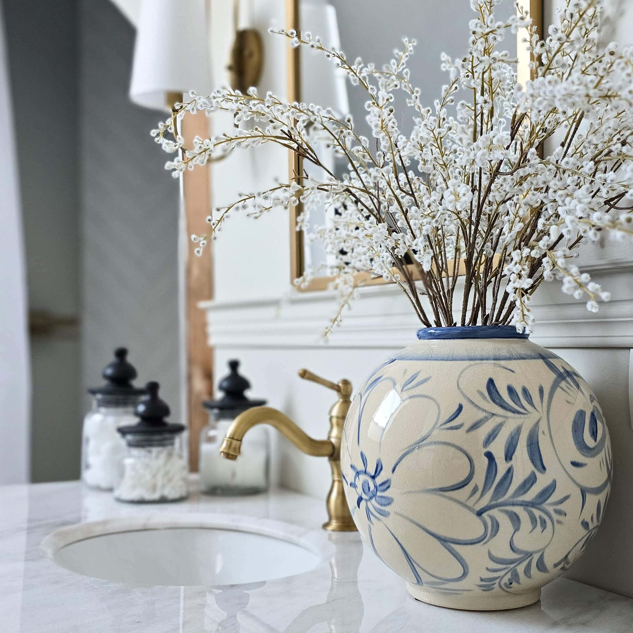 Vase en céramique ronde avec motif floral bleu sur un comptoir de salle de bain en marbre avec décoration