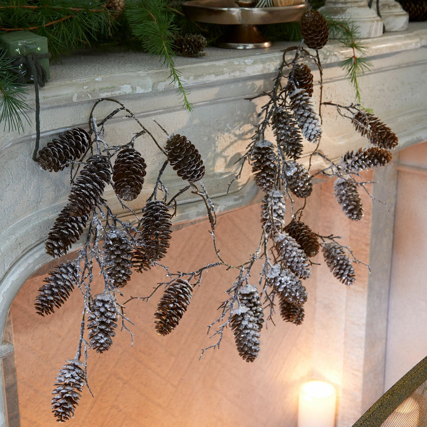 Guirlande Soralaith Branches de pommes de pin enneigées suspendues à une cheminée en pierre, décoration naturelle de Noël