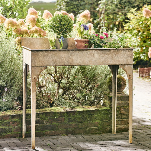 Table de jardin en métal beige avec des fleurs, parfaite pour cultiver des plantes en extérieur
