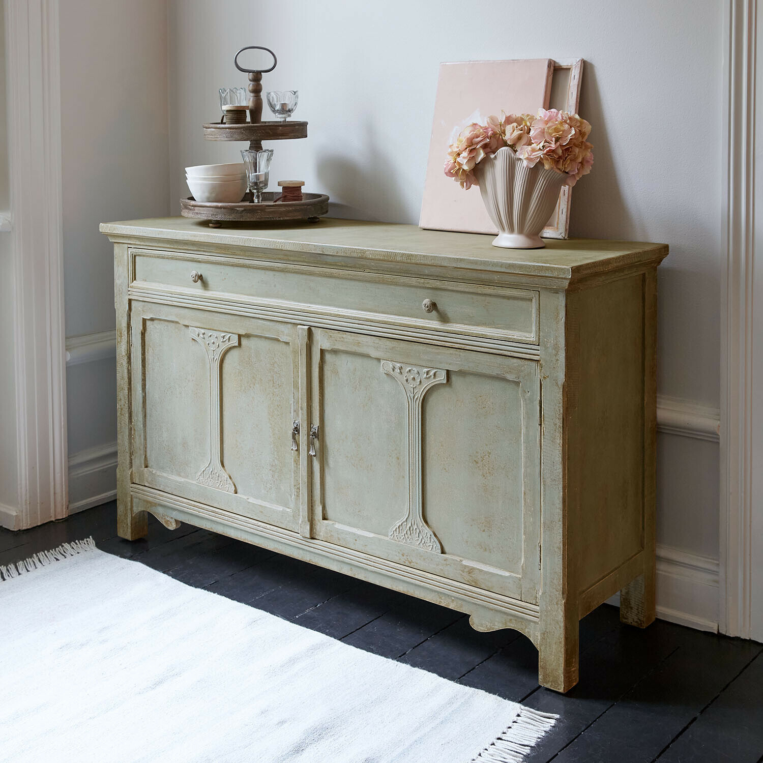 Commode Château Serein Buffet en bois vert avec portes décoratives et objets décoratifs posés dessus dans un intérieur élégant