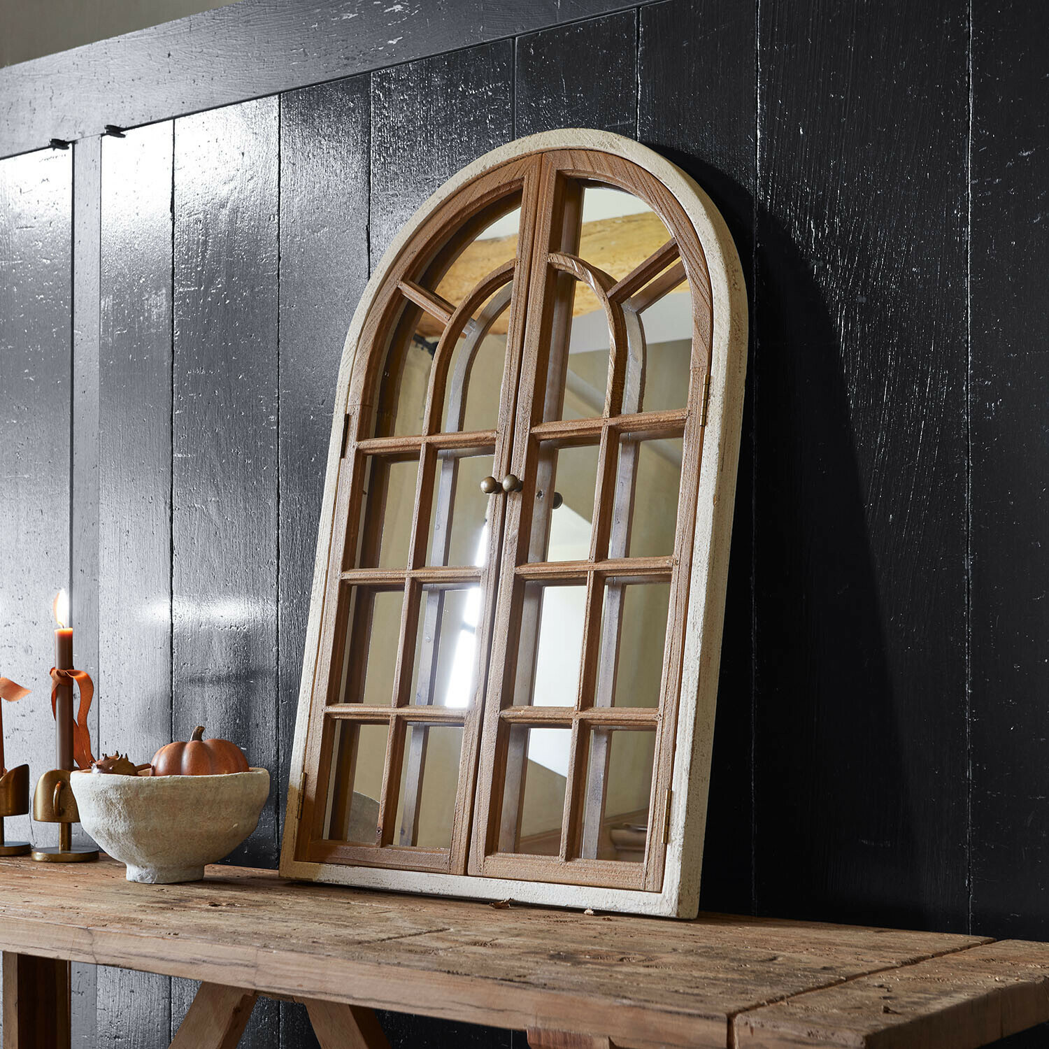 Fenêtre décorative avec miroir Montévine Miroir en bois en forme de fenêtre avec cadre blanc posé sur une table rustique devant un mur noir