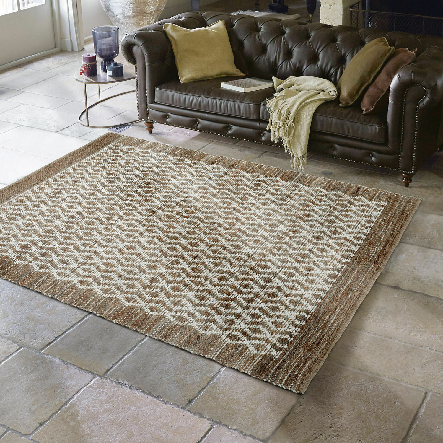 Tapis réversible Amhara Tapis marron et crème à motif géométrique sur sol en pierre devant un canapé en cuir marron foncé