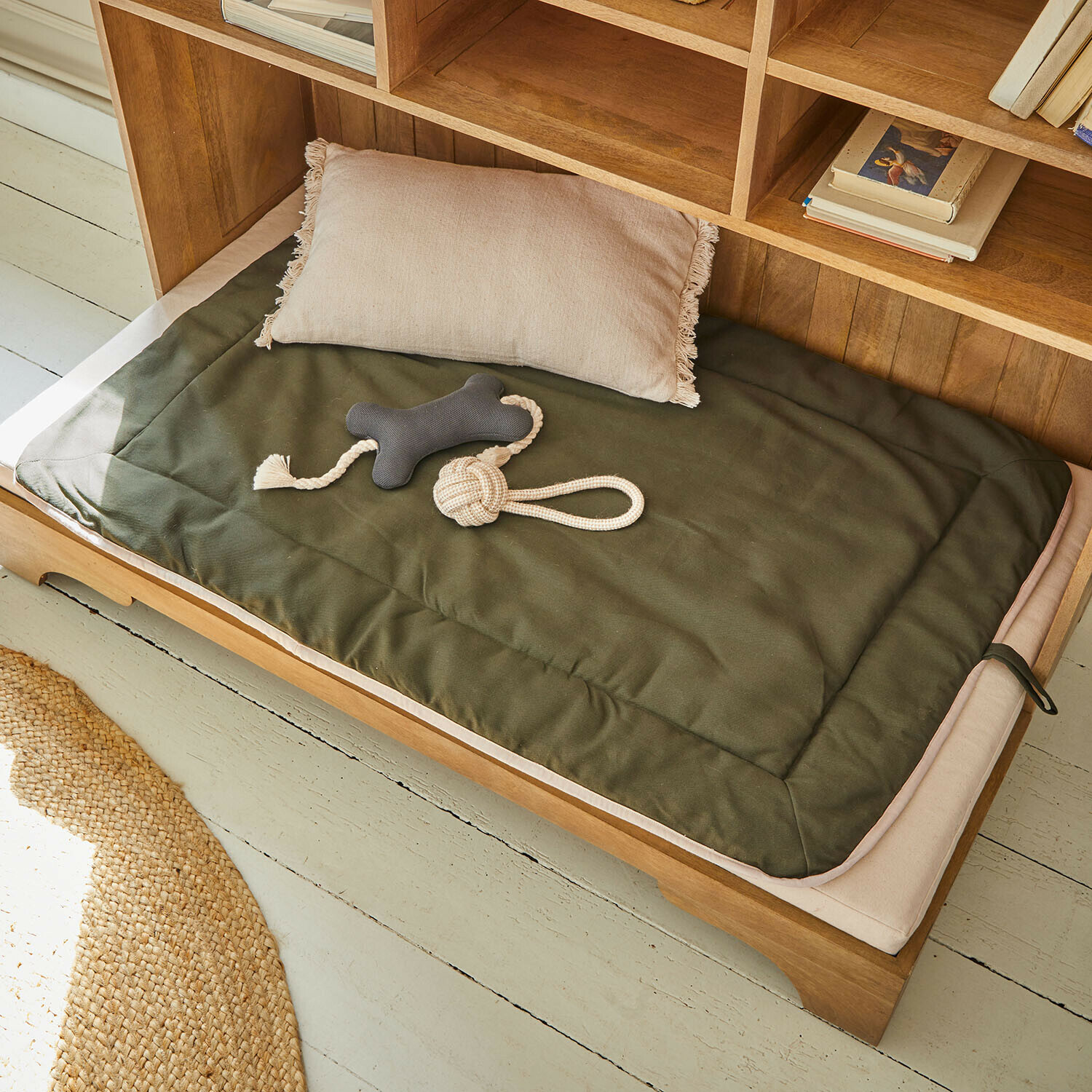 Tapis pour animaux Dunelyn Coussin et matelas vert en tissu sur lit en bois avec jouets pour chien dans un intérieur naturel