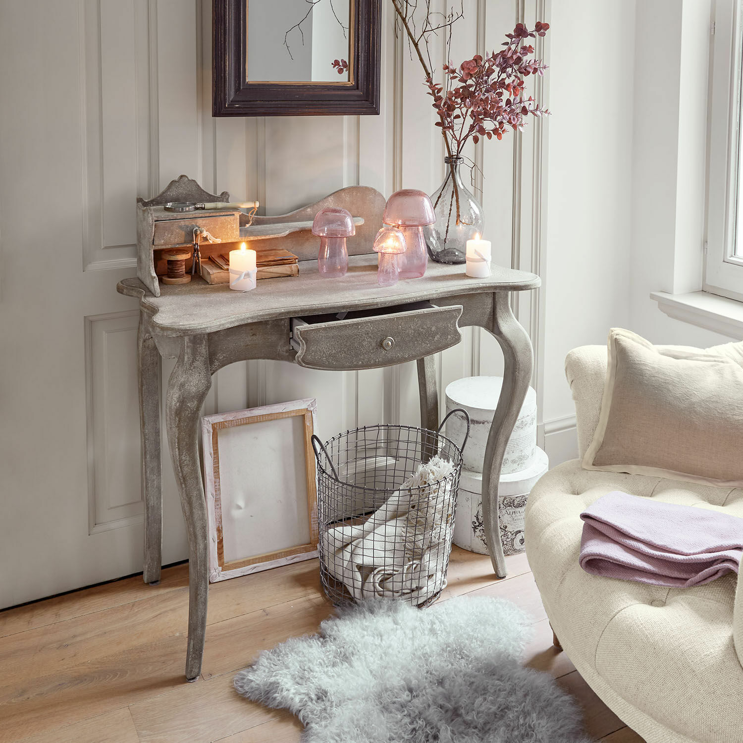 Console Loustain Console en bois grise avec tiroir, décorée de lanternes en verre rose et bougies dans un intérieur chaleureux