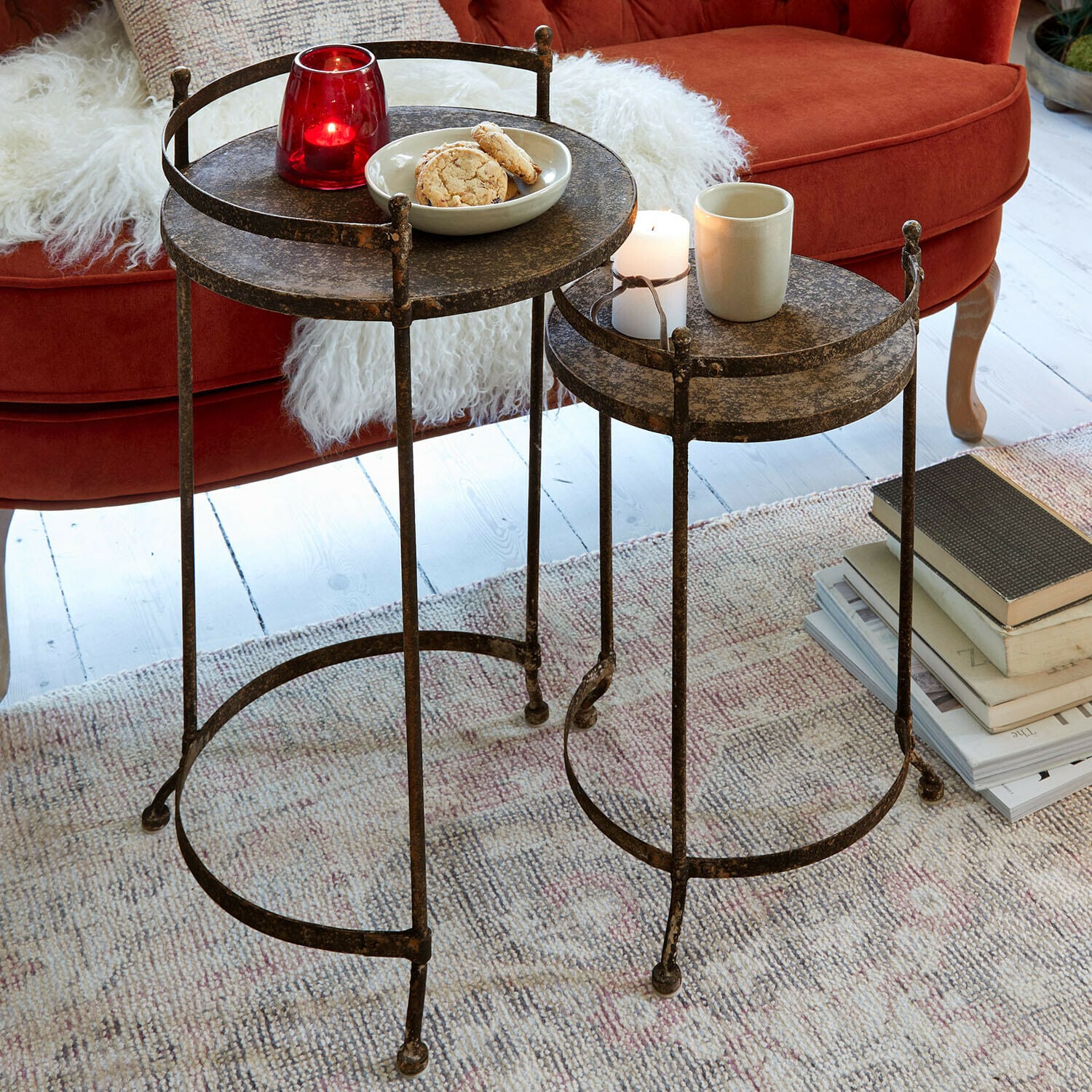 Lot de 2 tables d'appoint Alanyn Ensemble de deux tables d'appoint rondes en métal bronze vieilli sur tapis près d'un canapé rouge