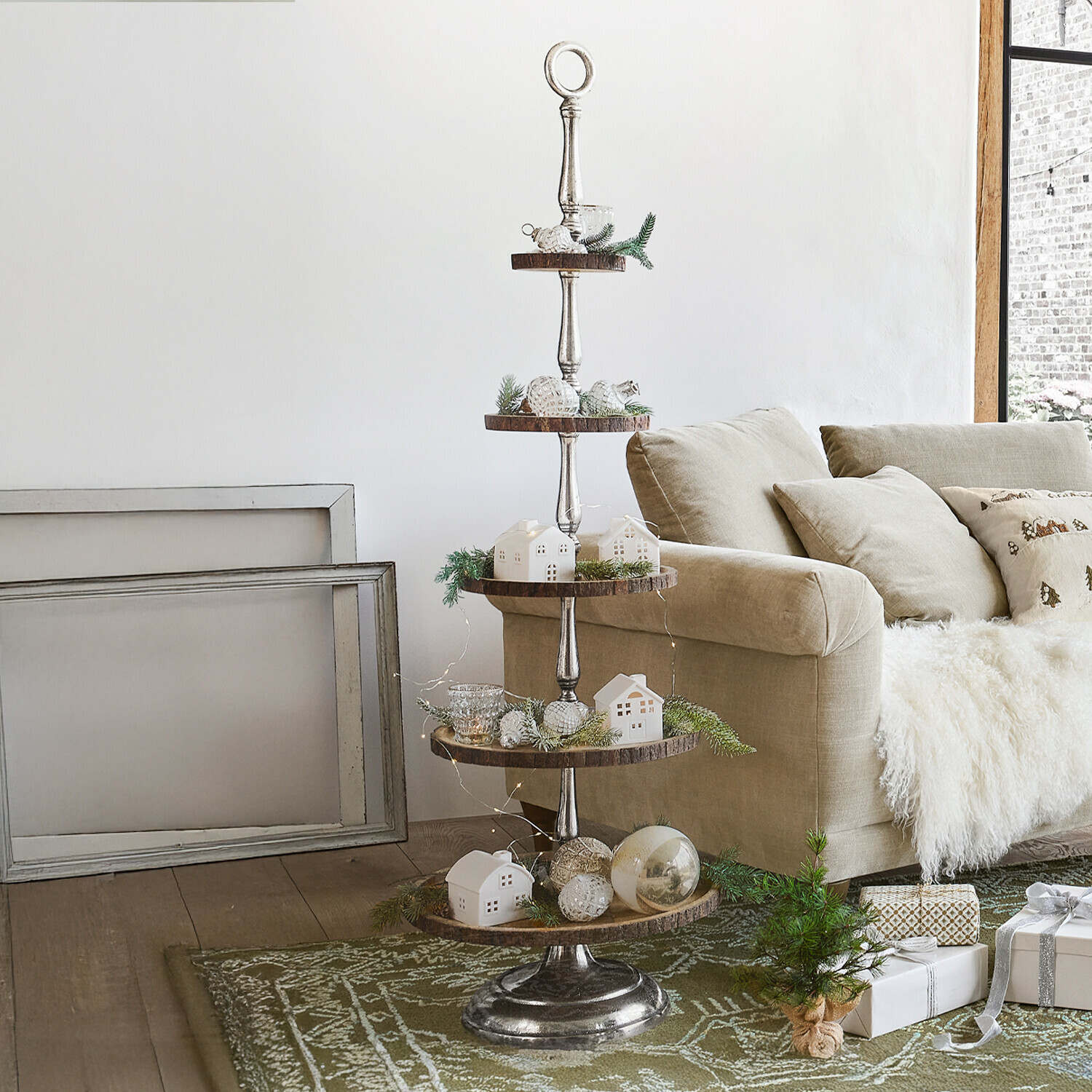Présentoir à étages Clarette Présentoir à plusieurs niveaux en métal et bois avec snacks près d'un canapé beige et décorations salon