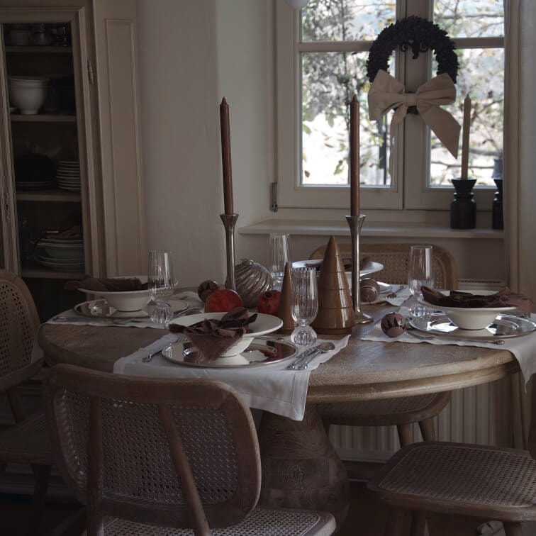 Table en bois rustique décorée pour les fêtes avec bougies marron dans une salle à manger chaleureuse